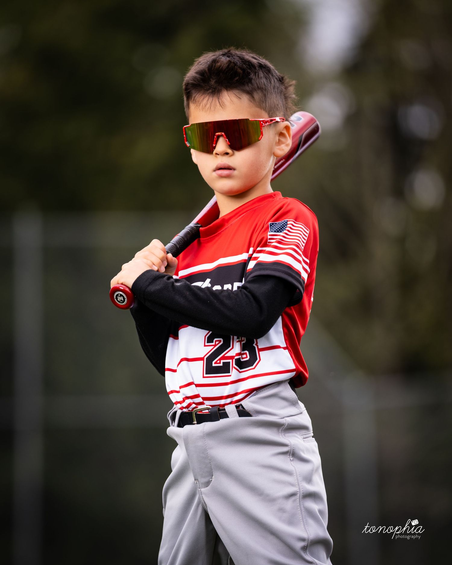 Baseball player in red and white uniform swings bat during practice session outdoors.