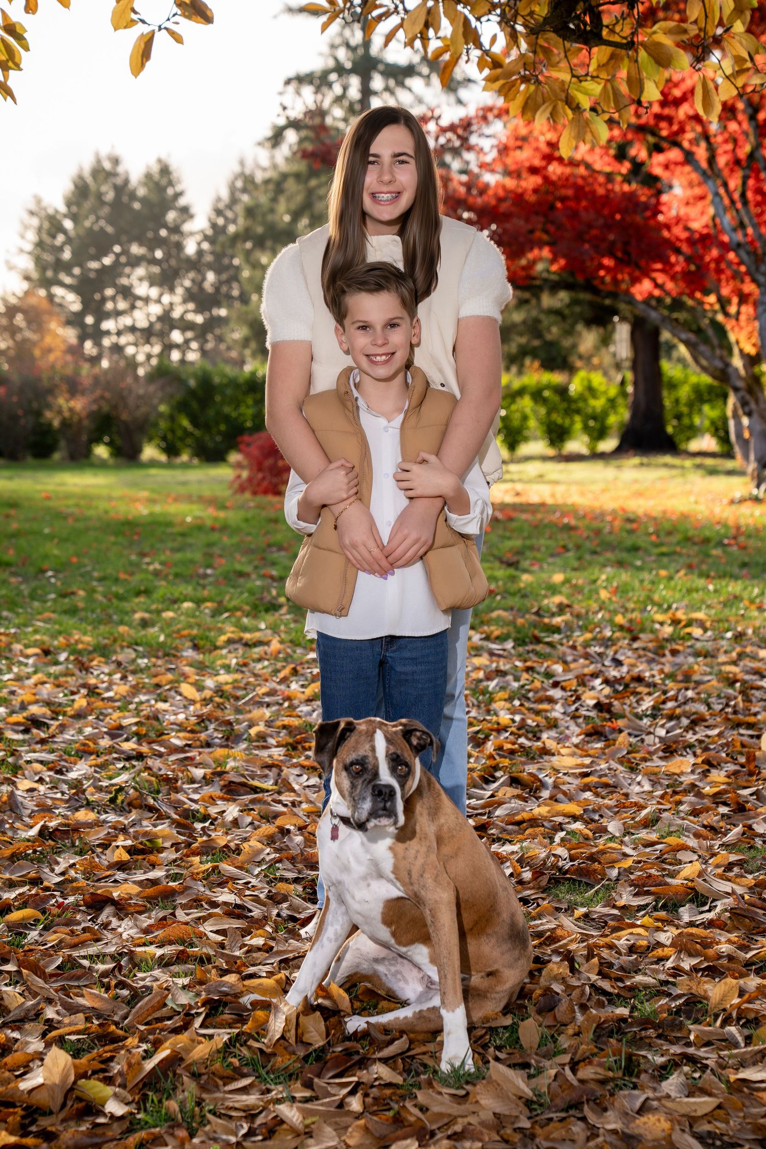 Autumn family photoshoot with a brown and white dog among fallen leaves.