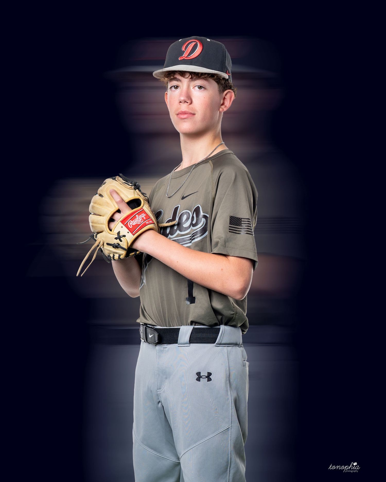 Baseball player in grey uniform and black cap poses in batting stance.