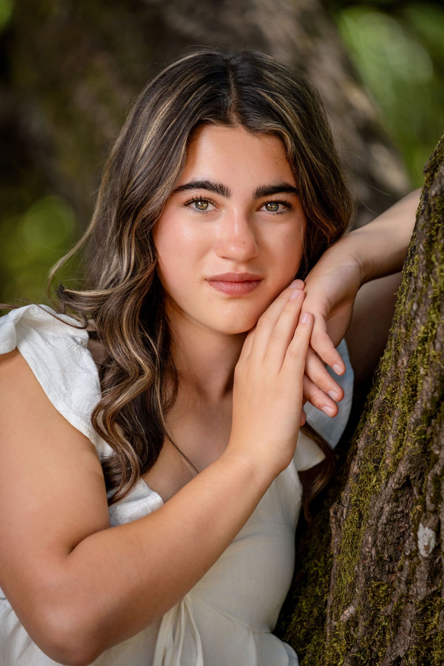 Close-up portrait against tree trunk in natural lighting.