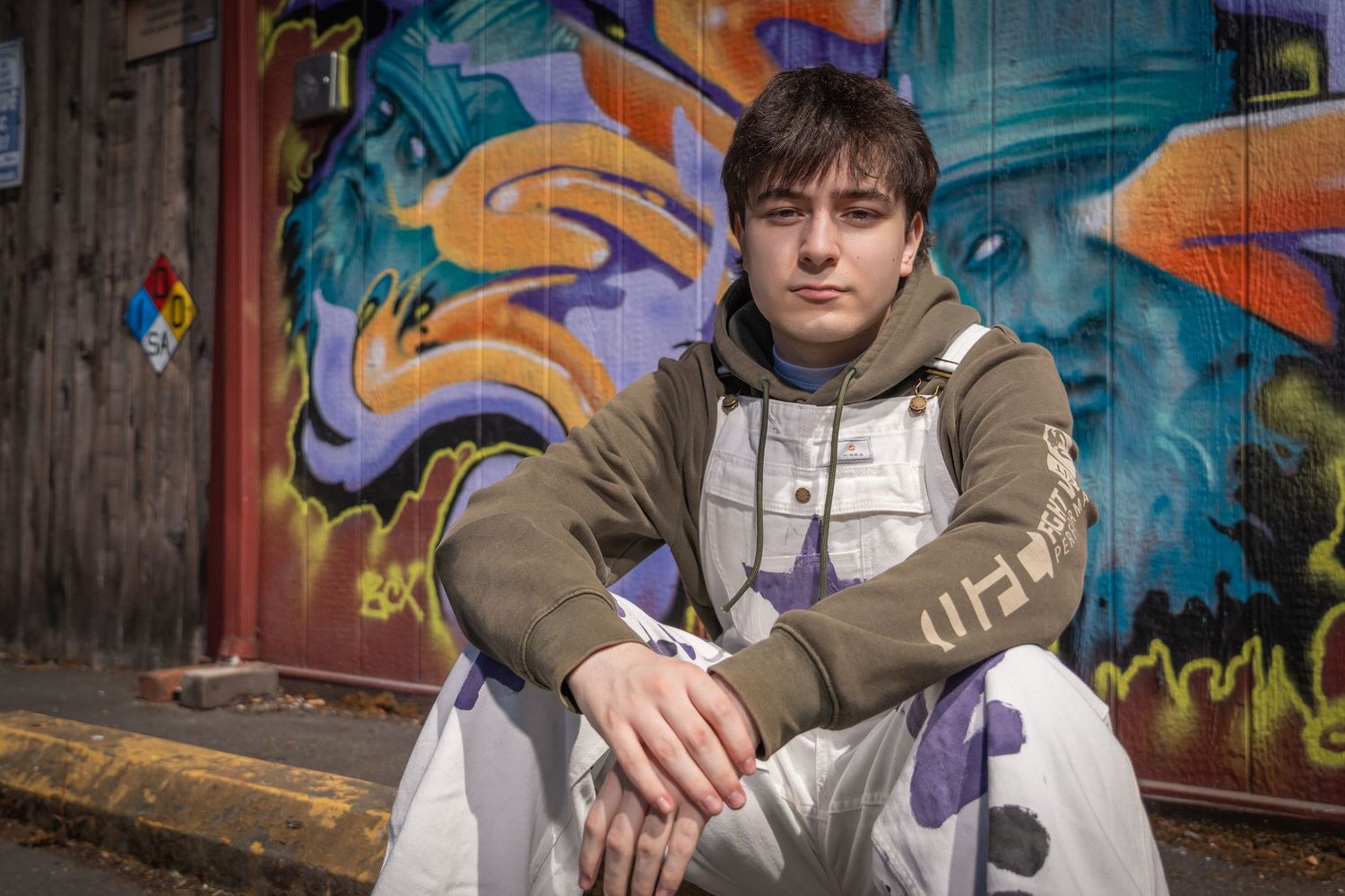 Urban photography against vibrant graffiti wall featuring casual street style.