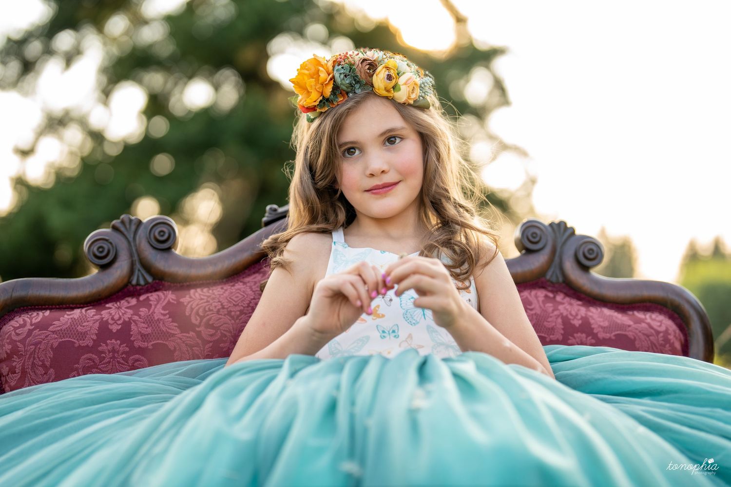 Formal portrait series in teal gown with floral crown outdoors at sunset.