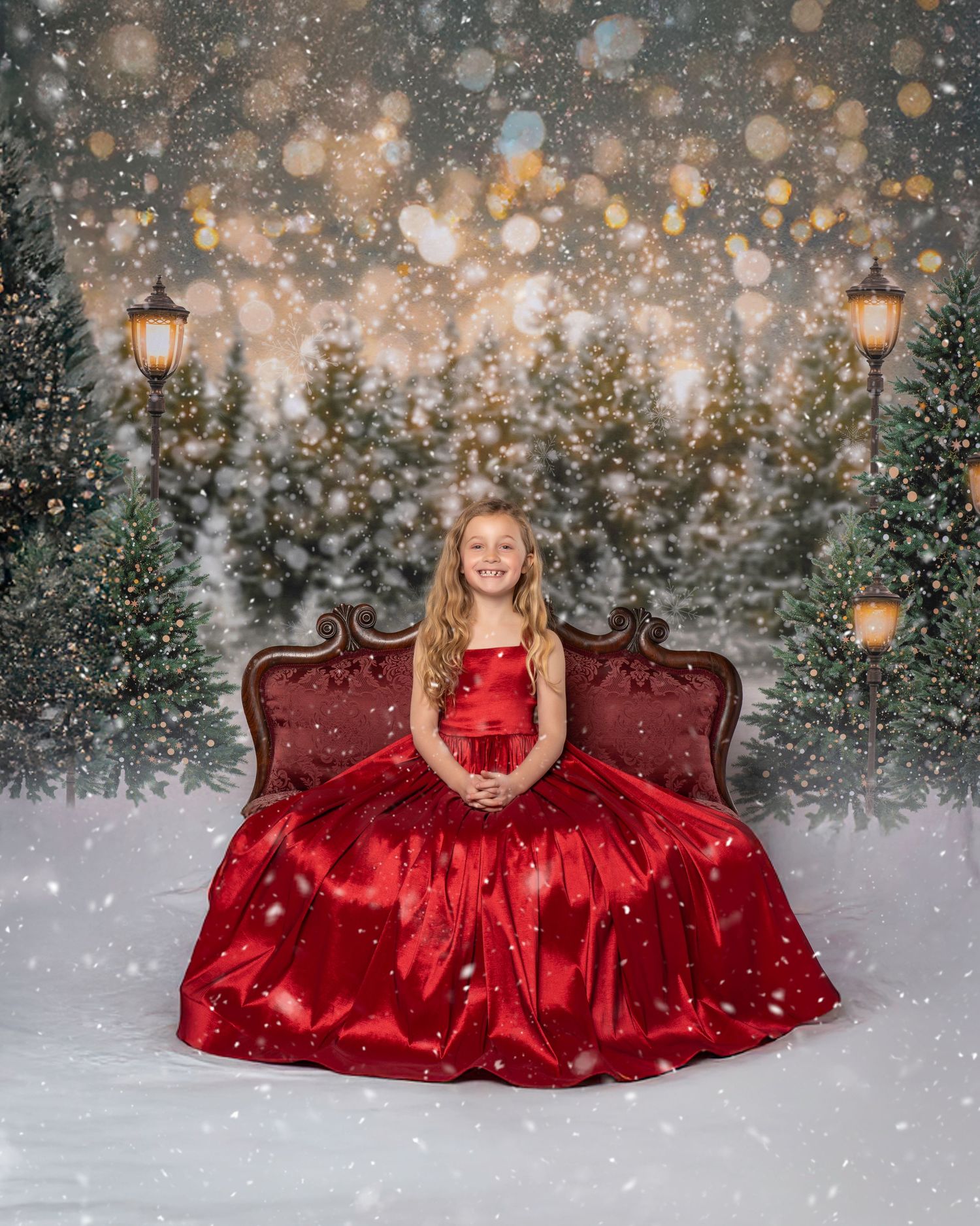 Winter portrait with red ball gown against snowy backdrop with twinkling lights.