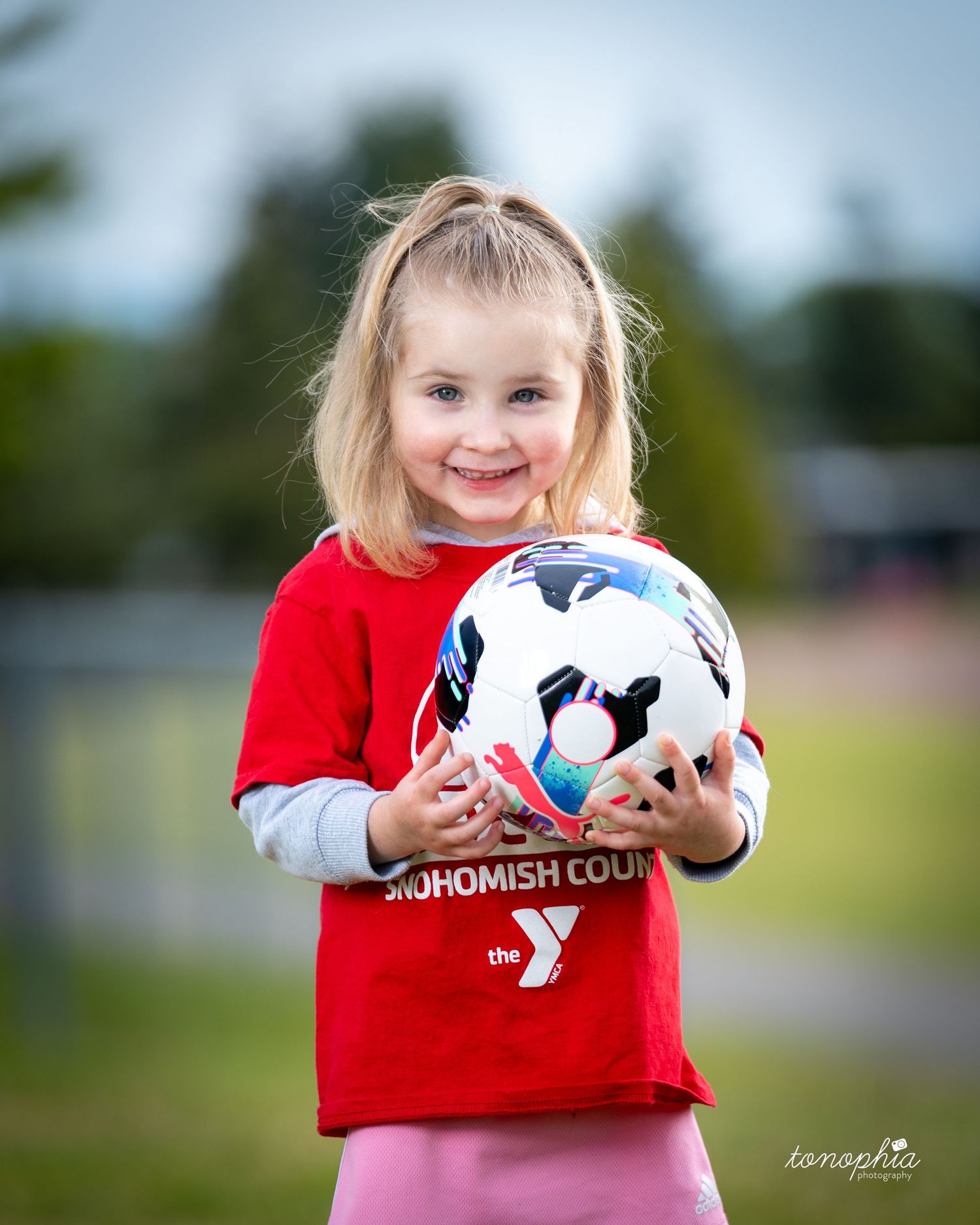 A soccer ball is held up against a blurred green outdoor background in a series of connected photos.