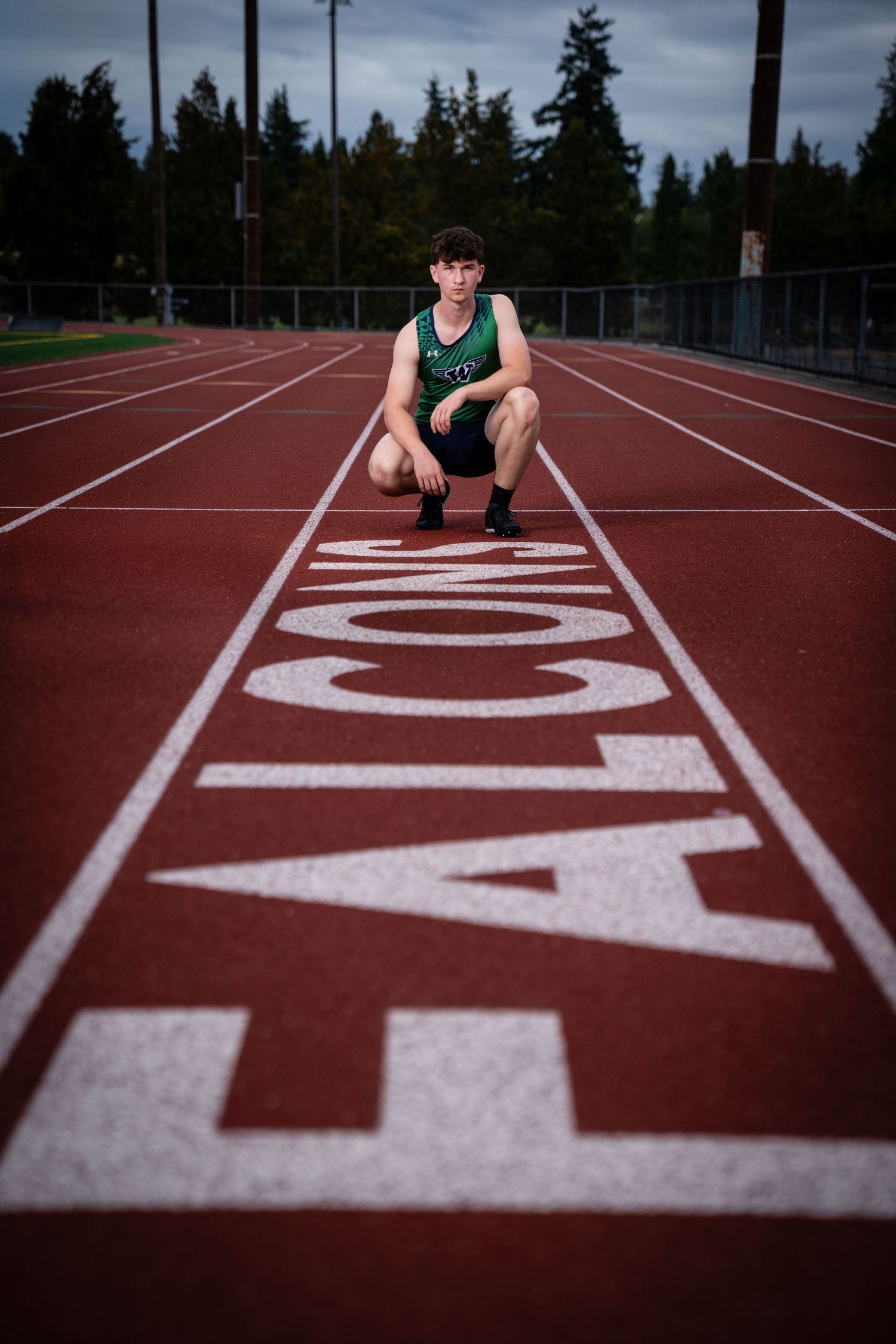 Track and field athlete sits on running track with lane numbers visible.