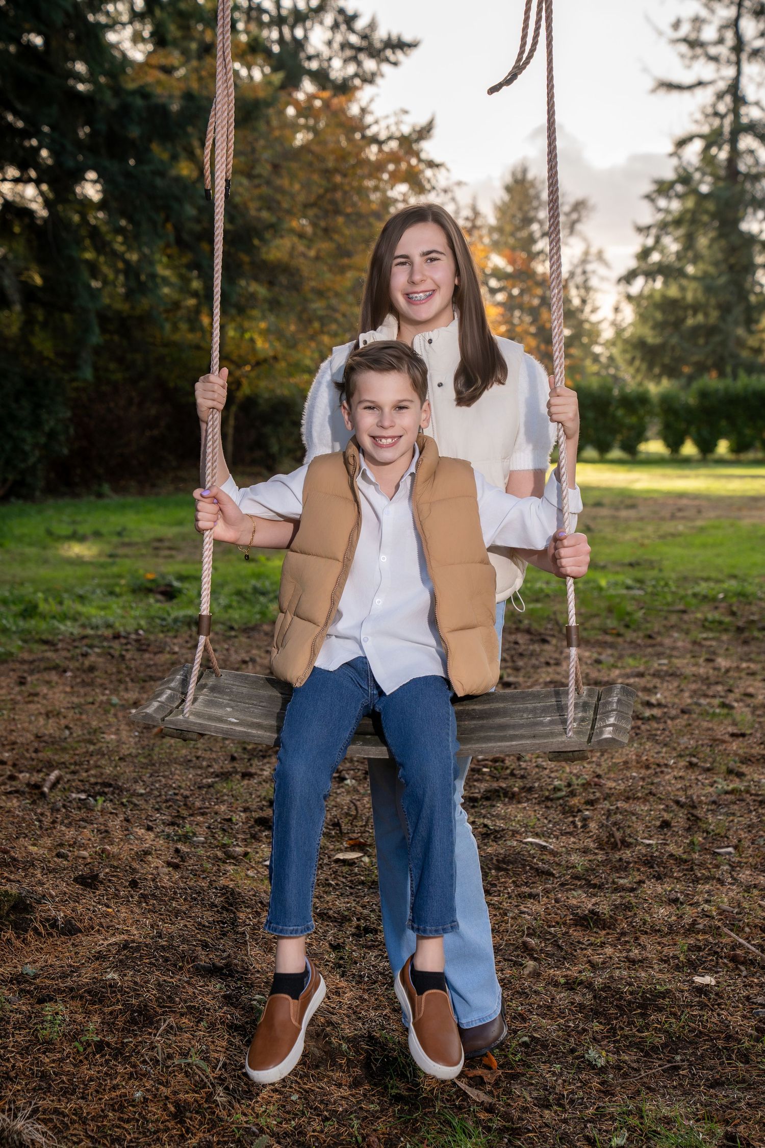 People enjoying a rustic rope swing during a fall photoshoot in a park setting.