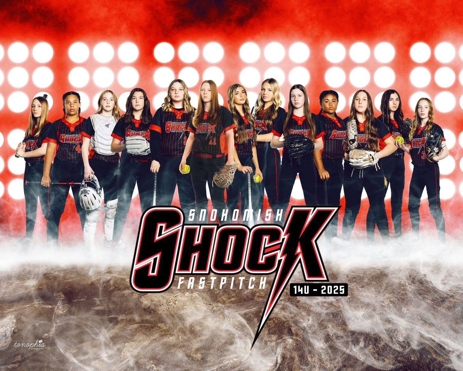 Women's softball team poses in dramatic lighting wearing black uniforms.