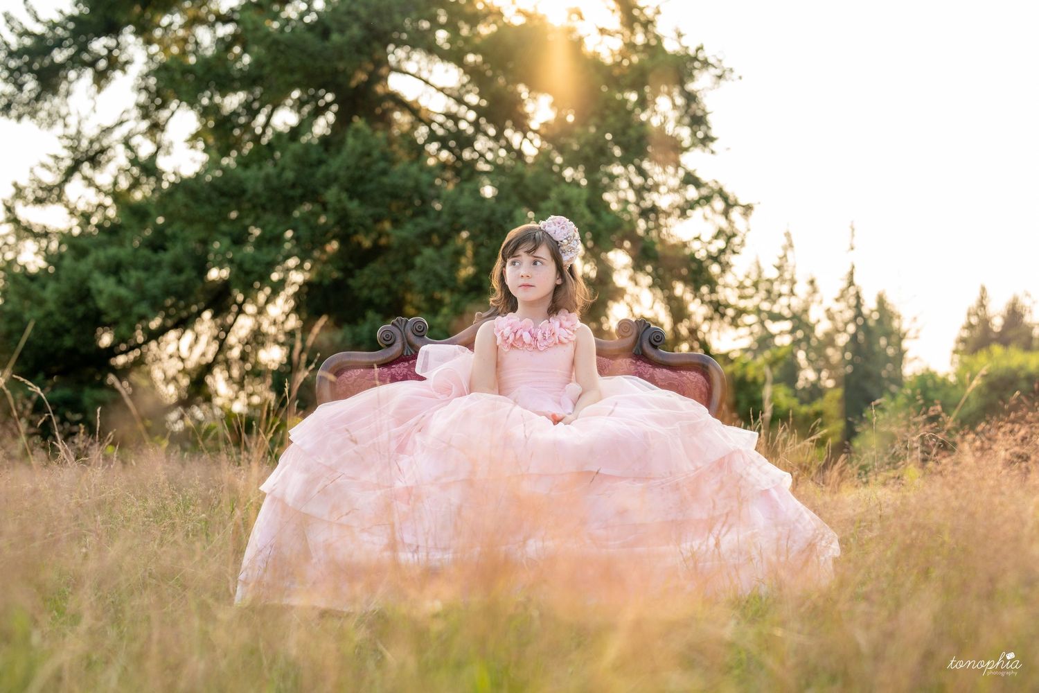 A dreamy sunset photoshoot in a golden field with soft sunlight filtering through trees.