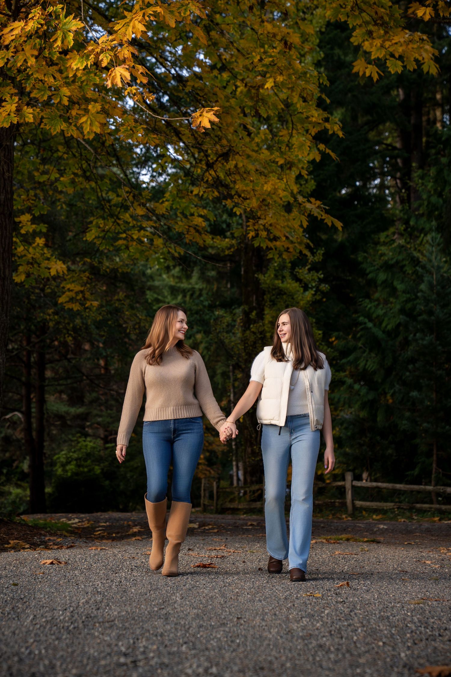 Two people walking together on a path surrounded by golden autumn foliage.