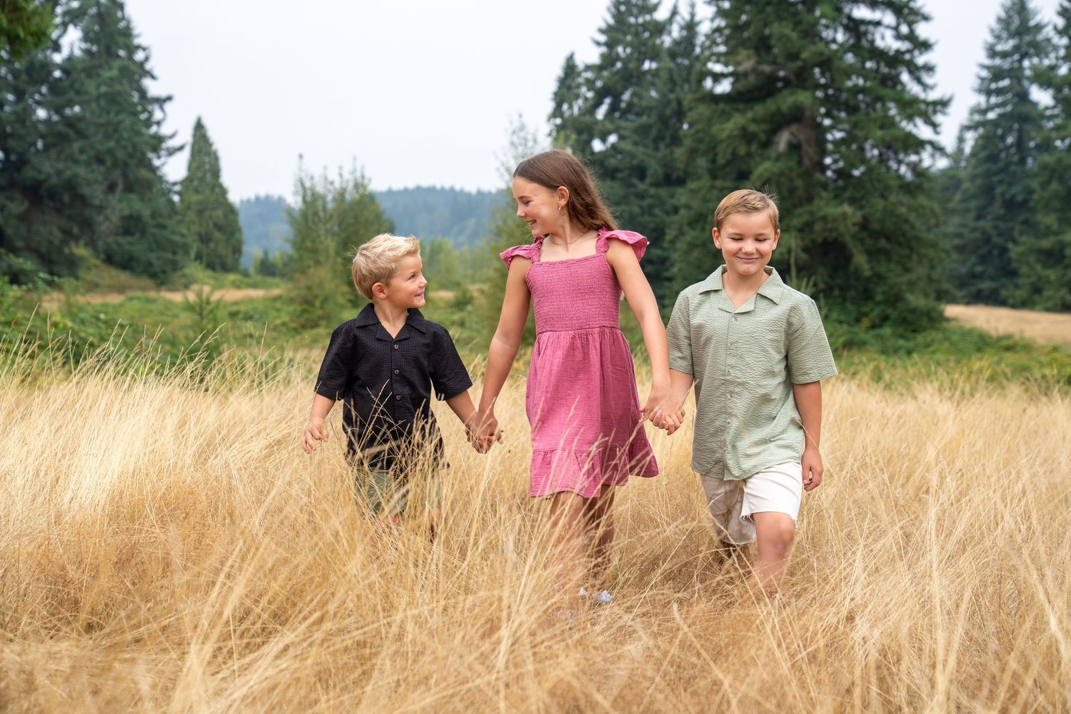 Family walking together through golden wheat field on sunny summer day.