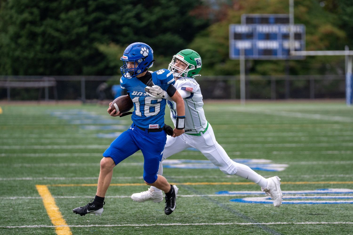 Football players from opposing teams engage in a running play on the field.