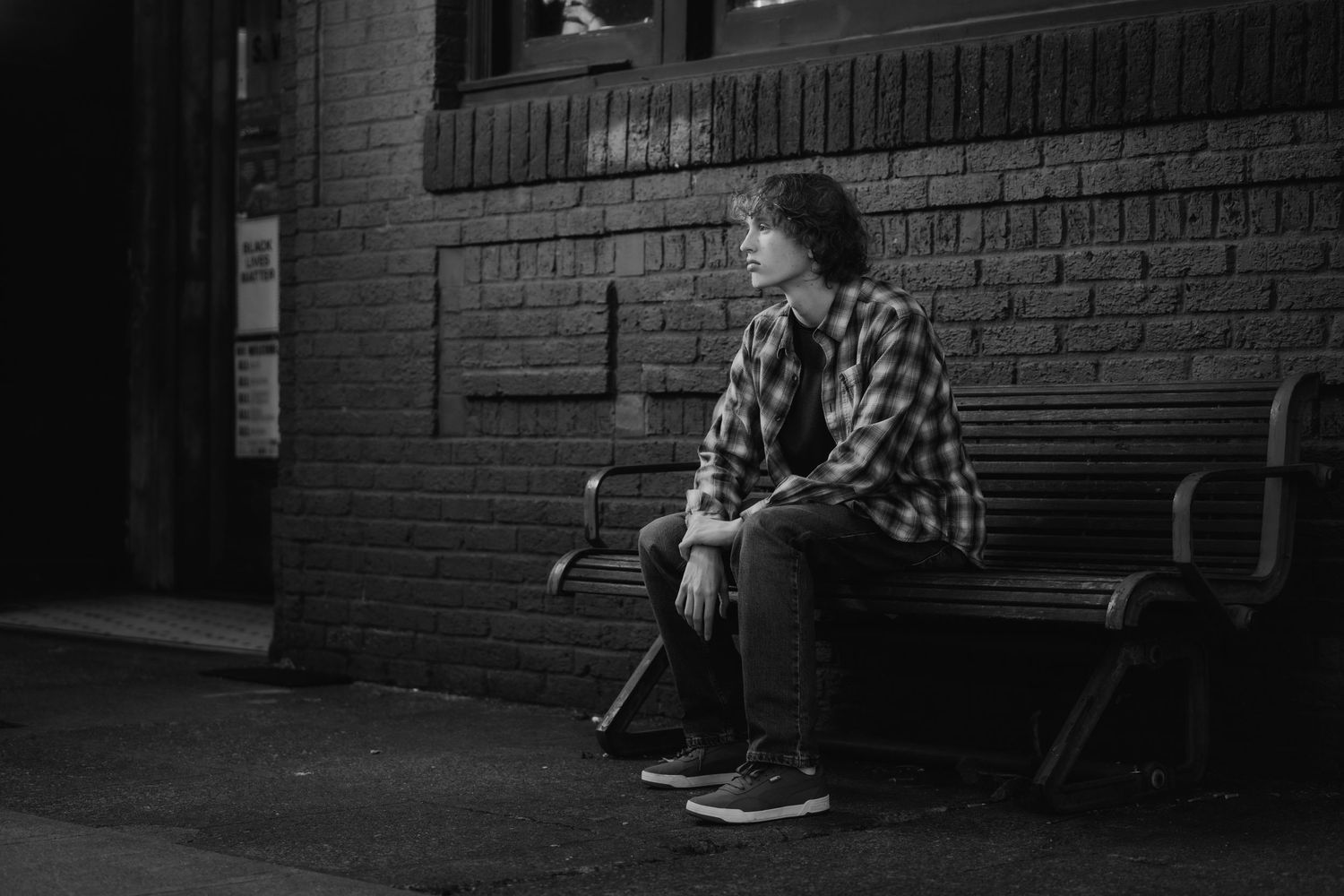 Dark atmospheric shots along a brick building with benches and windows.