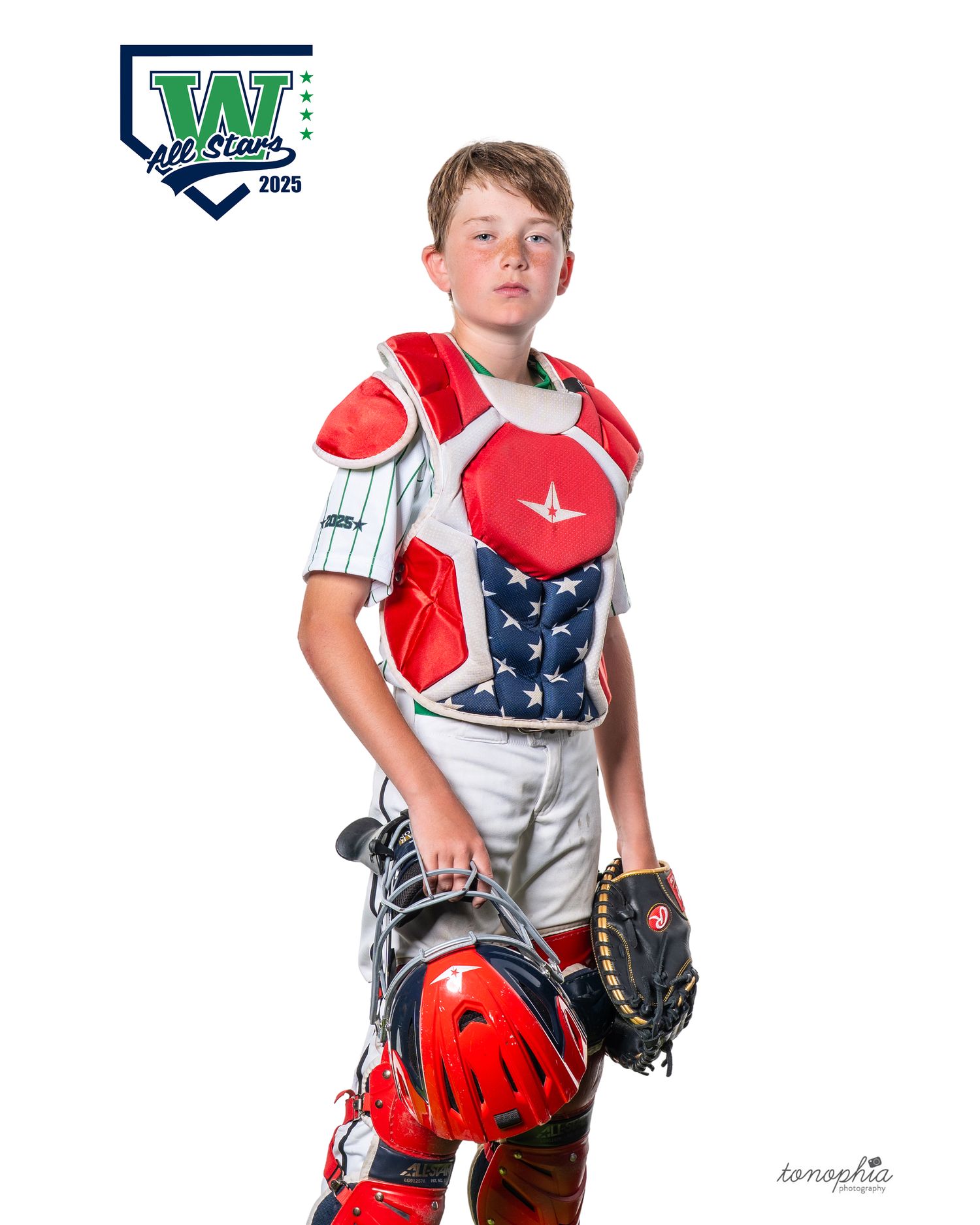 Youth baseball catcher poses in patriotic gear against white background.