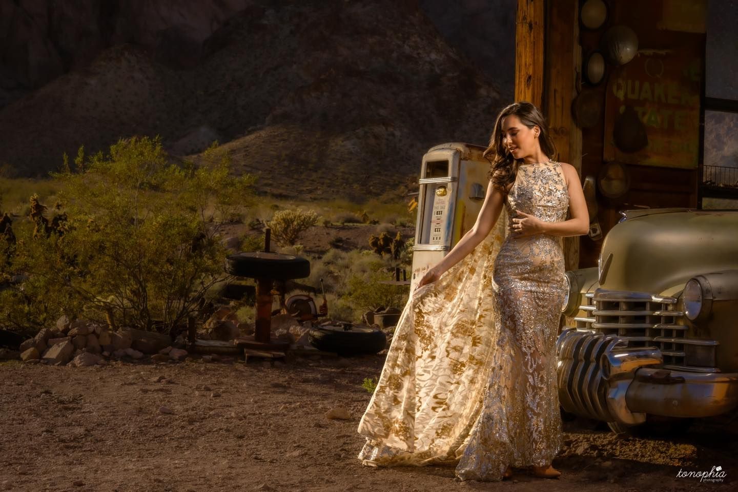 Elegant desert photoshoot featuring flowing dress against rugged rock formations at golden hour.