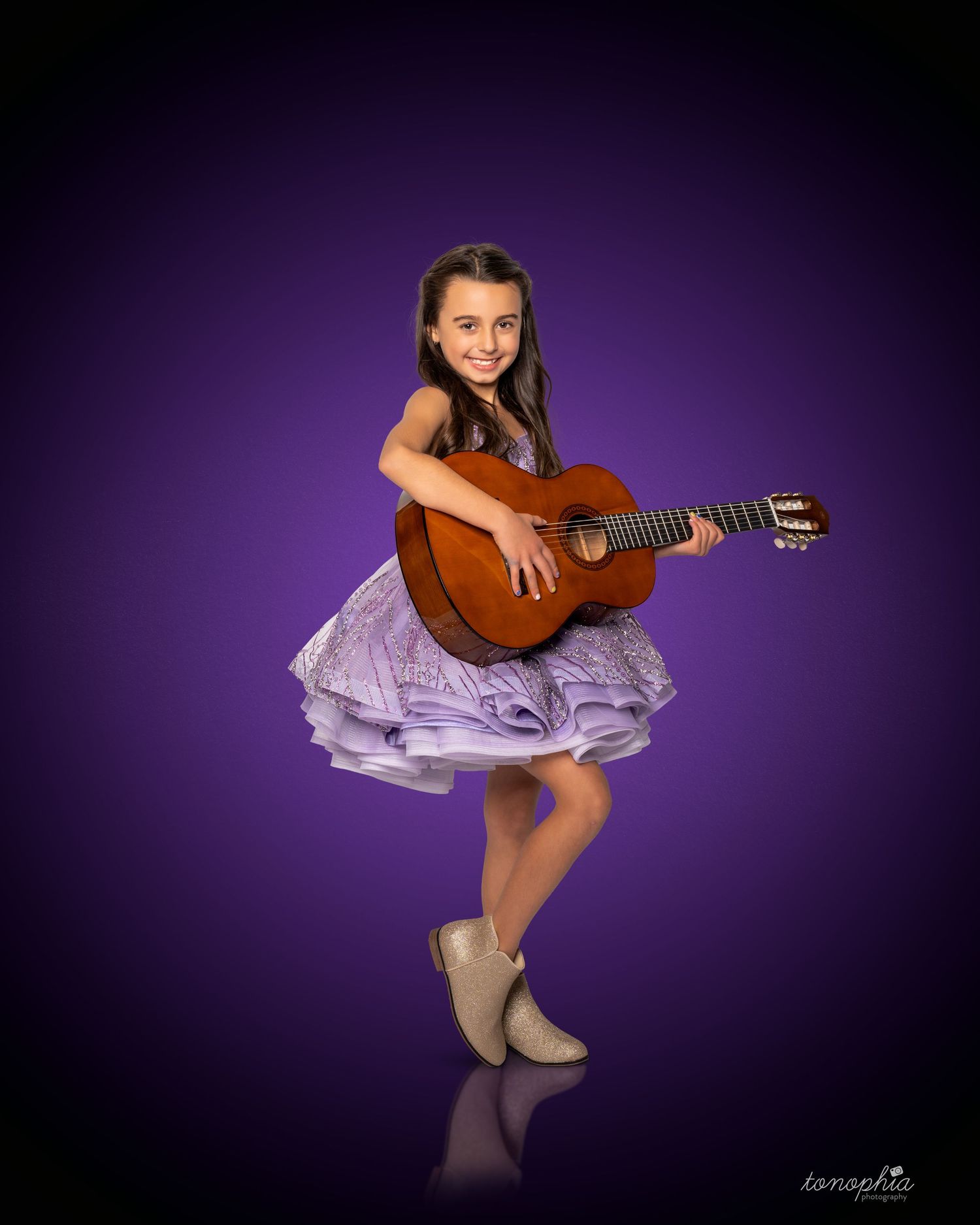A musical themed studio shoot featuring a classical guitar and lavender tulle dress against purple backdrop.