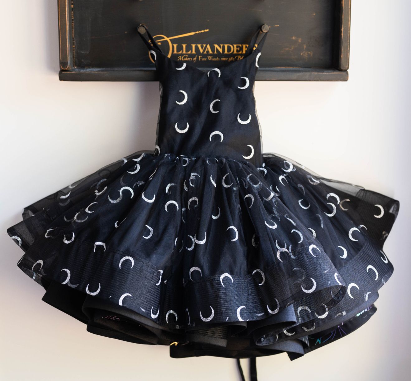 Black tutu dress with crescent moon pattern displayed on mannequin.
