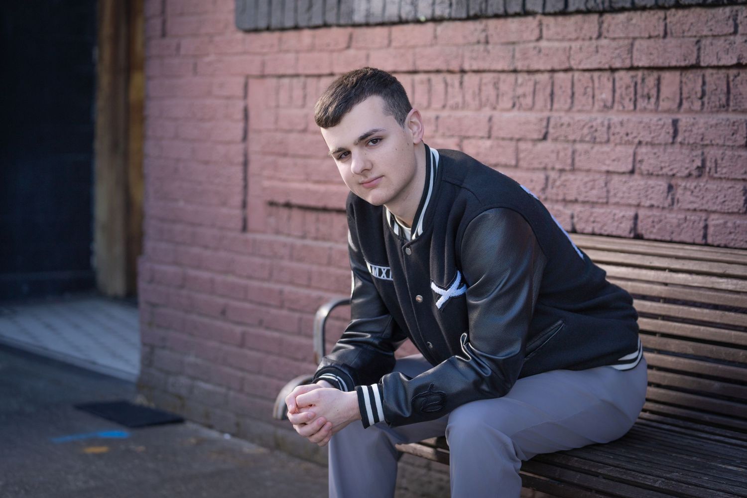 Urban portrait series against a pink brick wall showing casual poses.