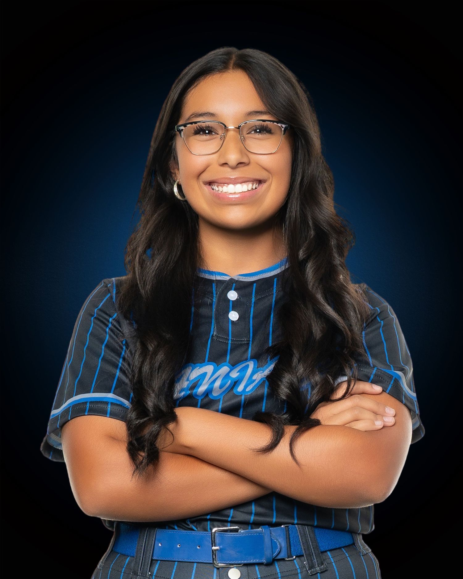 Softball player in blue pinstriped uniform poses confidently against dark background.