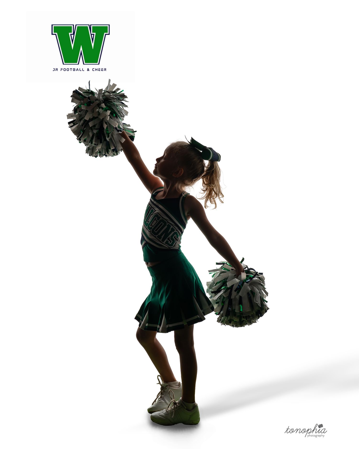 Young cheerleader in green uniform performs with pom poms against white background.