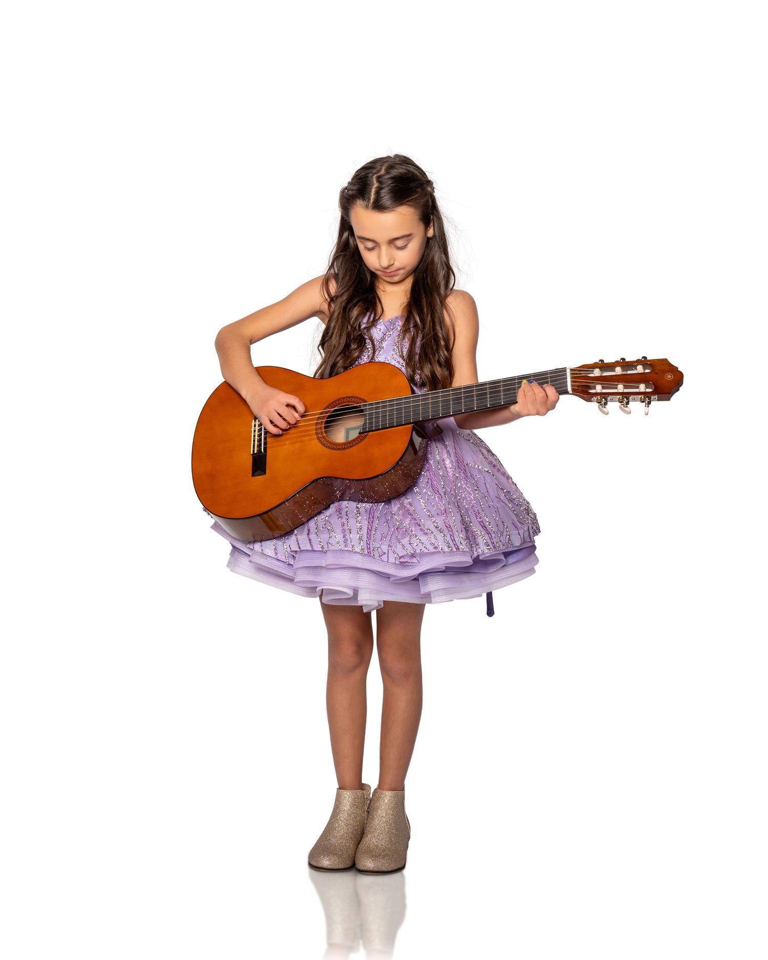 Young musician in purple dress playing acoustic guitar while seated in three progressive poses.