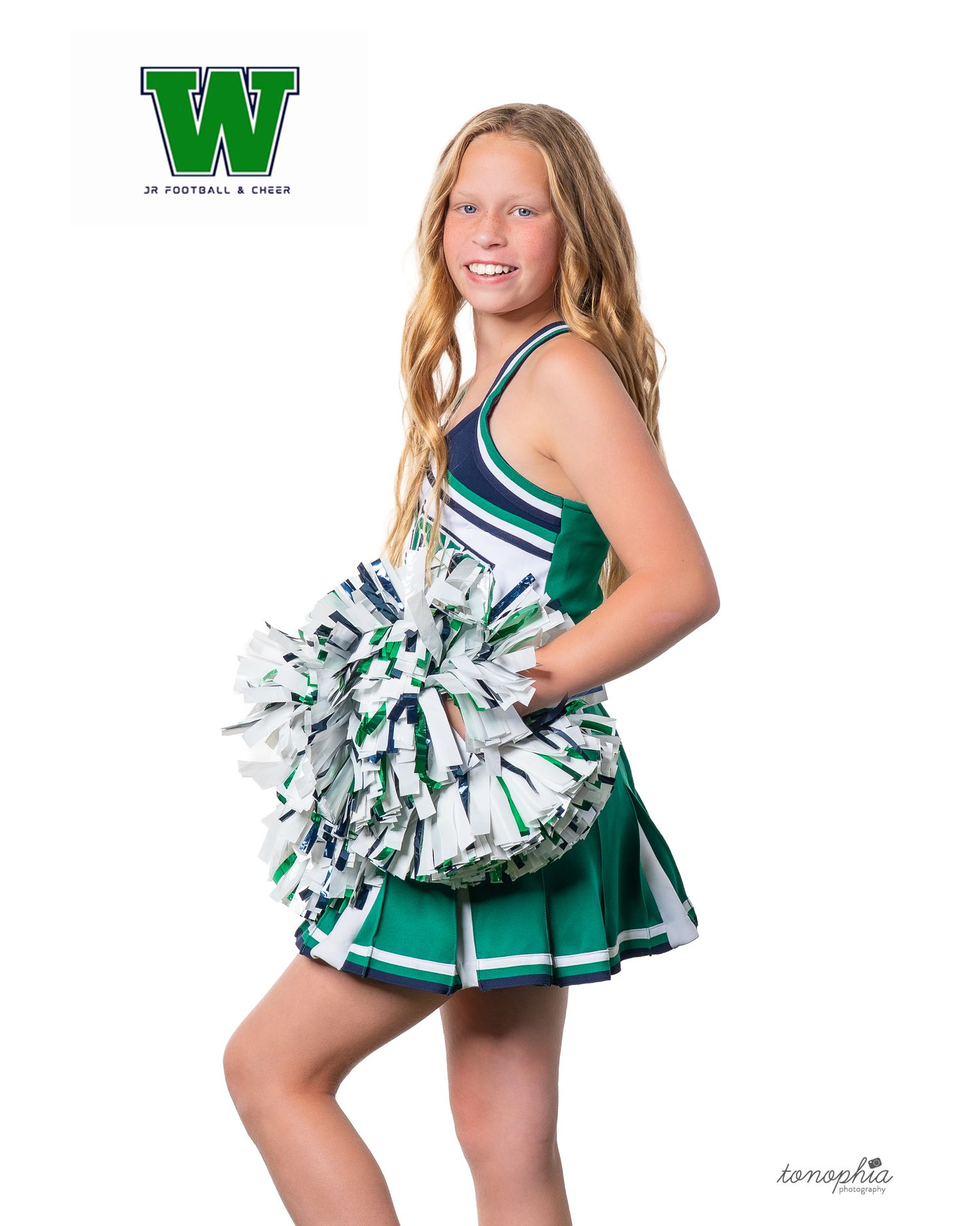 Cheerleader poses with silver pom-poms in green and white uniform against white background.