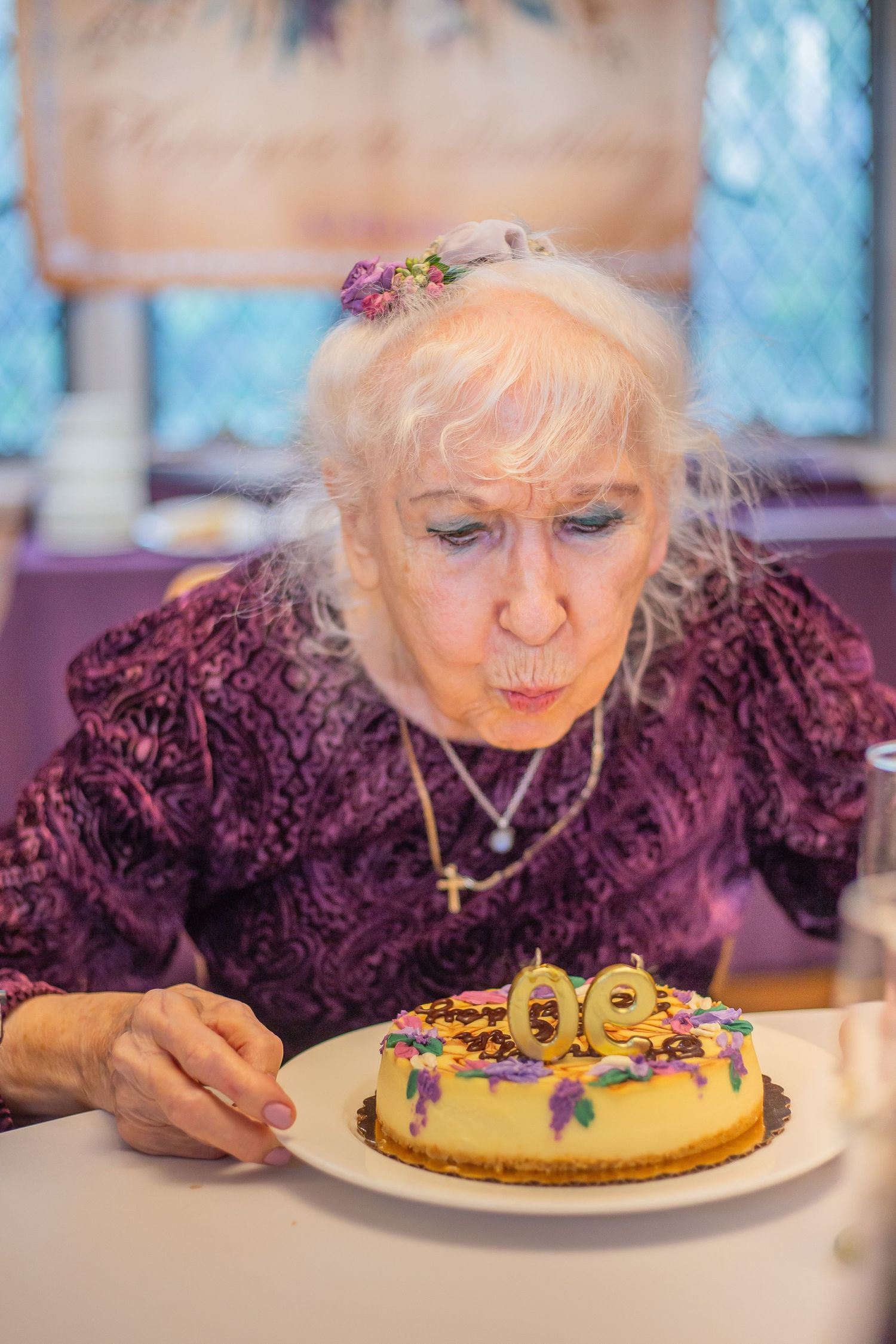 Elderly woman in purple sweater blowing out candles on a decorated birthday cake in sequence of celebration photos.