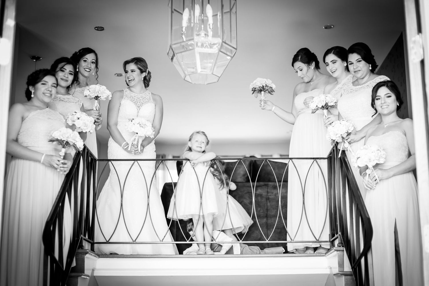 Black and white panoramic photo showing a wedding party lined up at a reception with elegant decor and lighting.