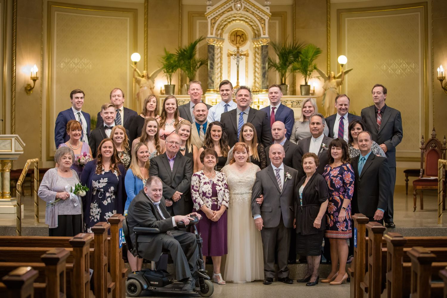 Wedding guests gather in rows inside an elegant church sanctuary with warm lighting and traditional wooden pews.