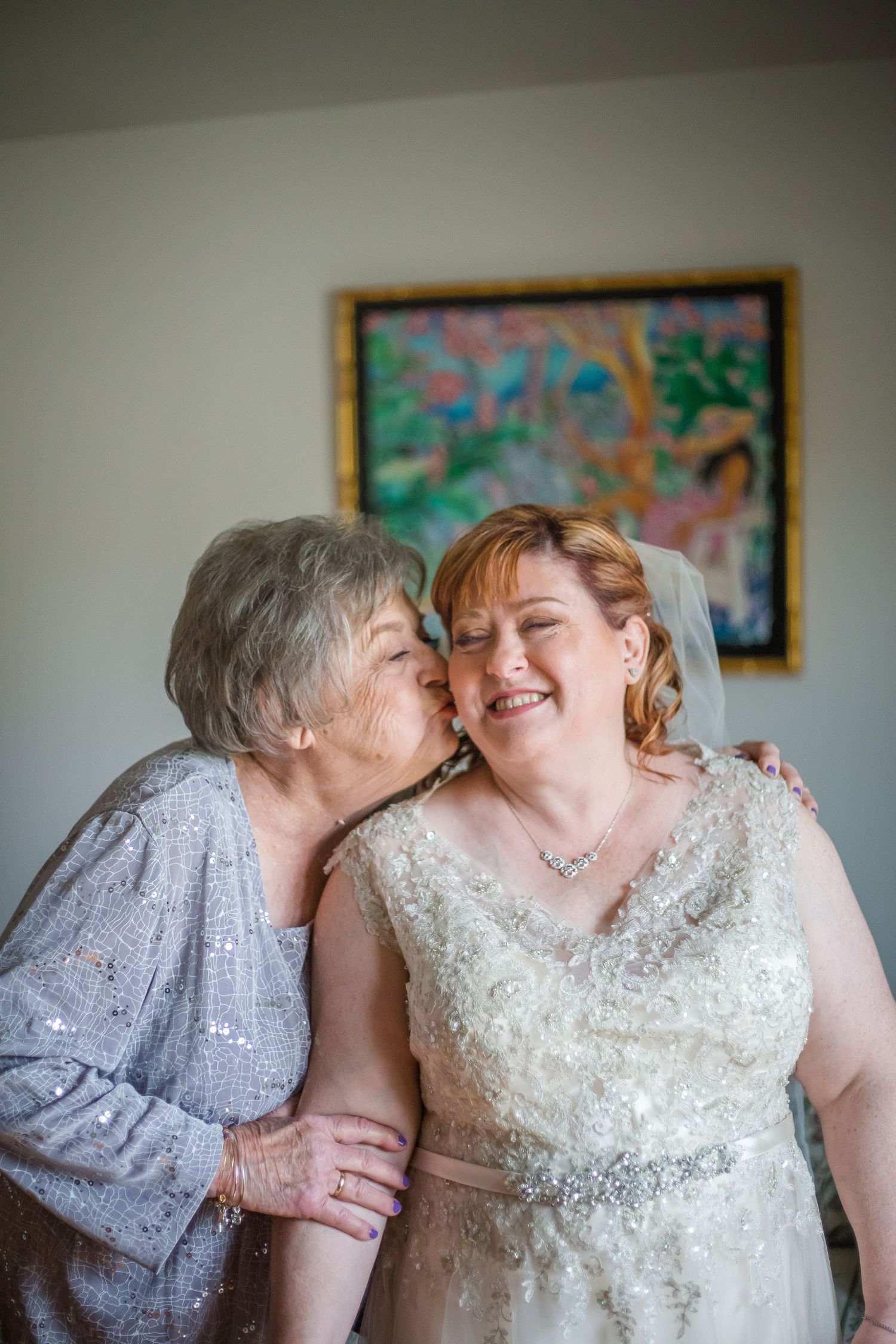 Two people in wedding attire share an intimate moment while smiling and embracing.