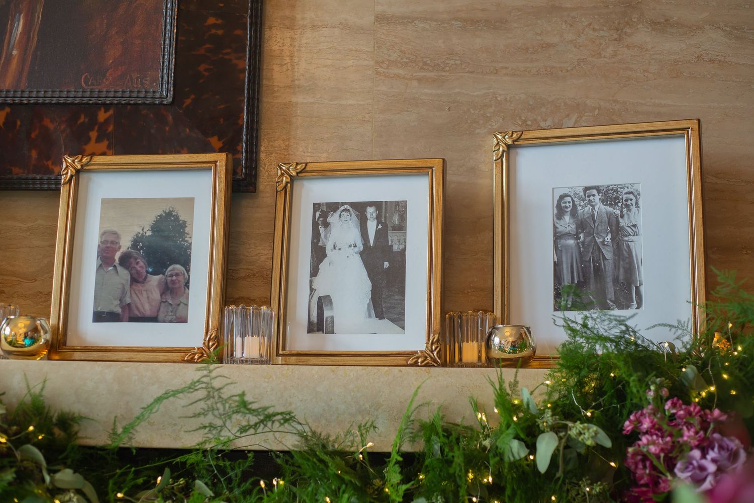A row of framed photographs displayed on a wooden wall with decorative flowers and greenery along the bottom edge.