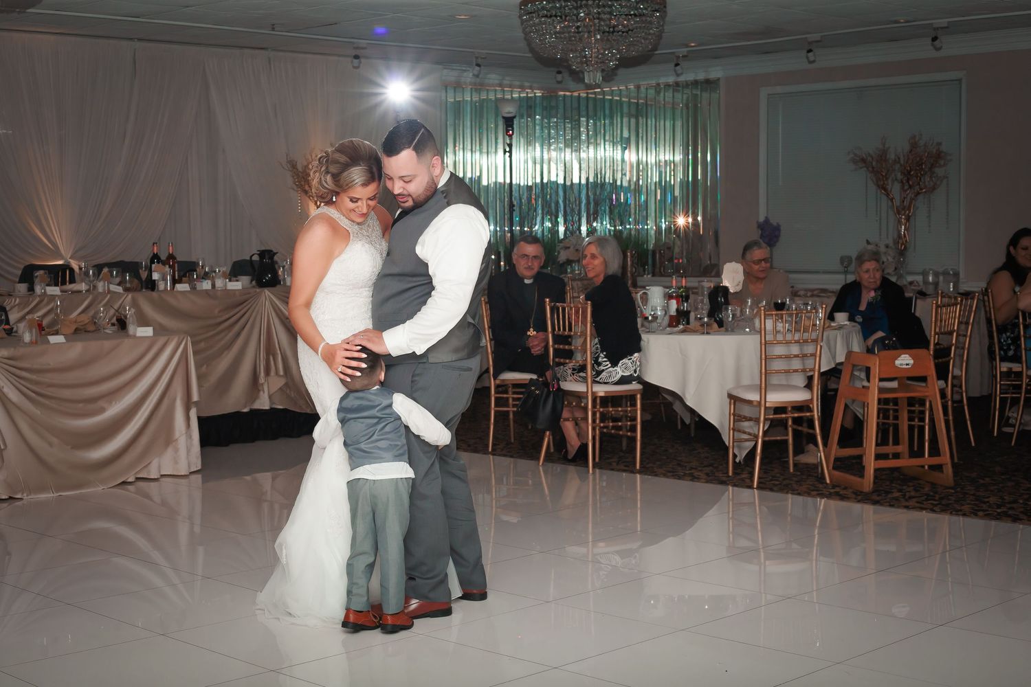 Couple dancing together on a wedding reception dance floor under elegant lighting and decor.