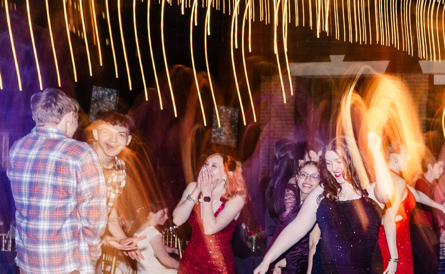 People dancing and having fun at a lively party or nightclub with colorful lighting effects.