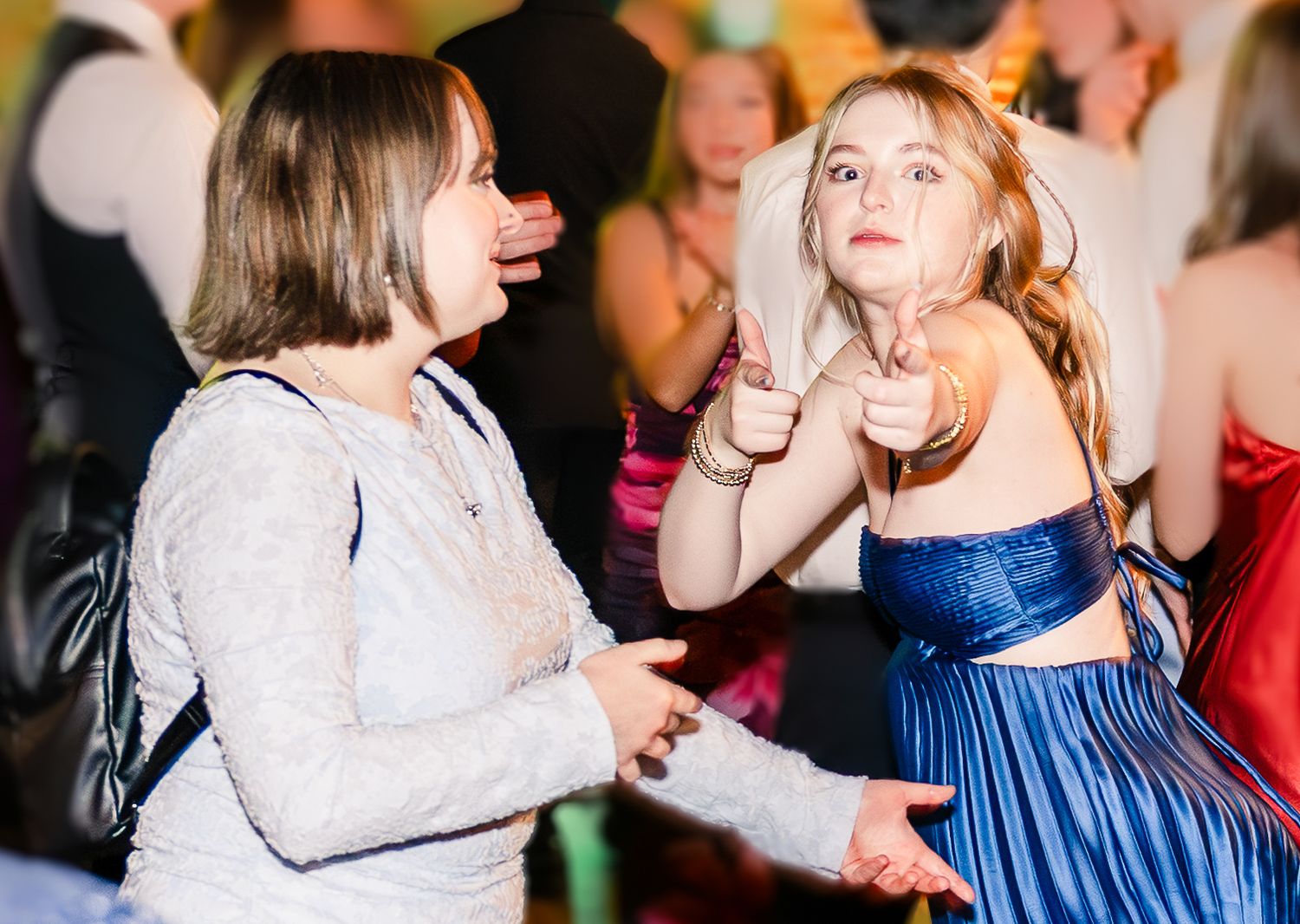 Children dance together at a party wearing colorful dresses and casual attire.