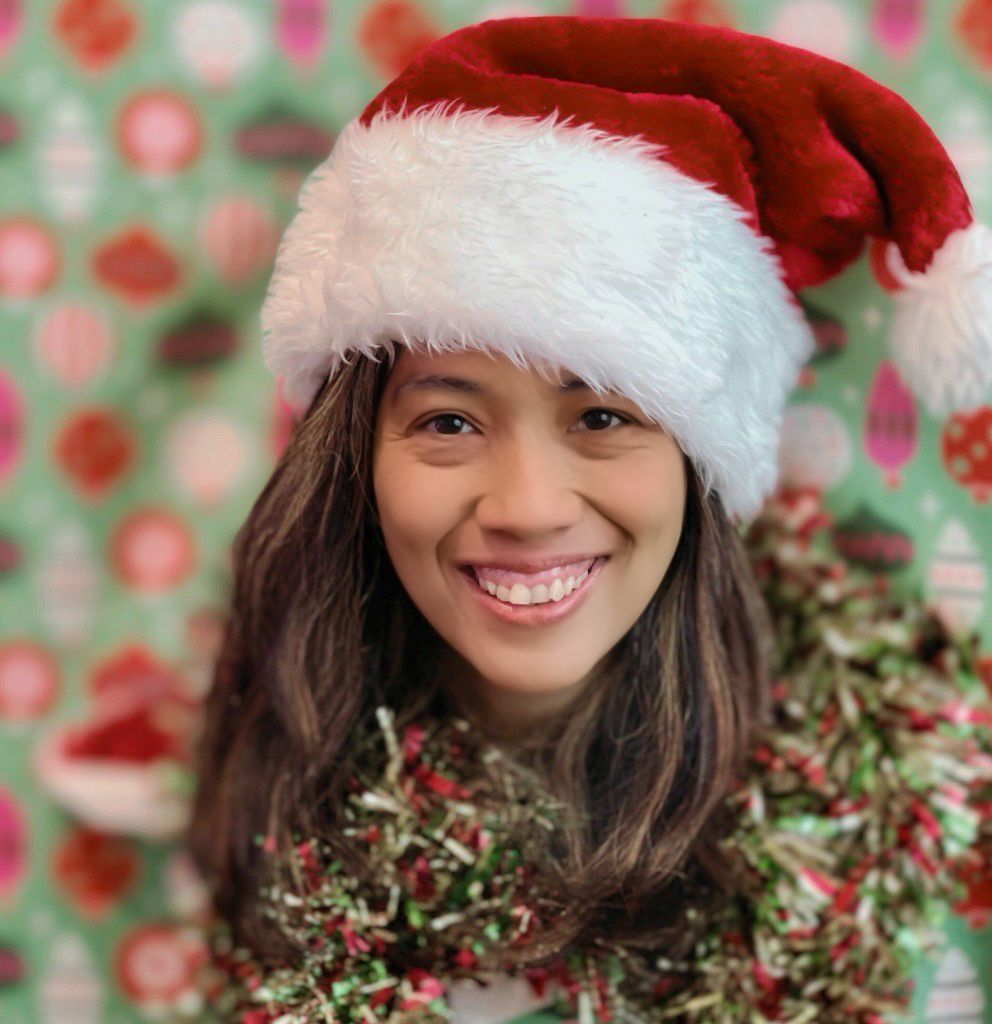 A festive holiday portrait with a white Santa hat and red berries against a blurred bokeh background.