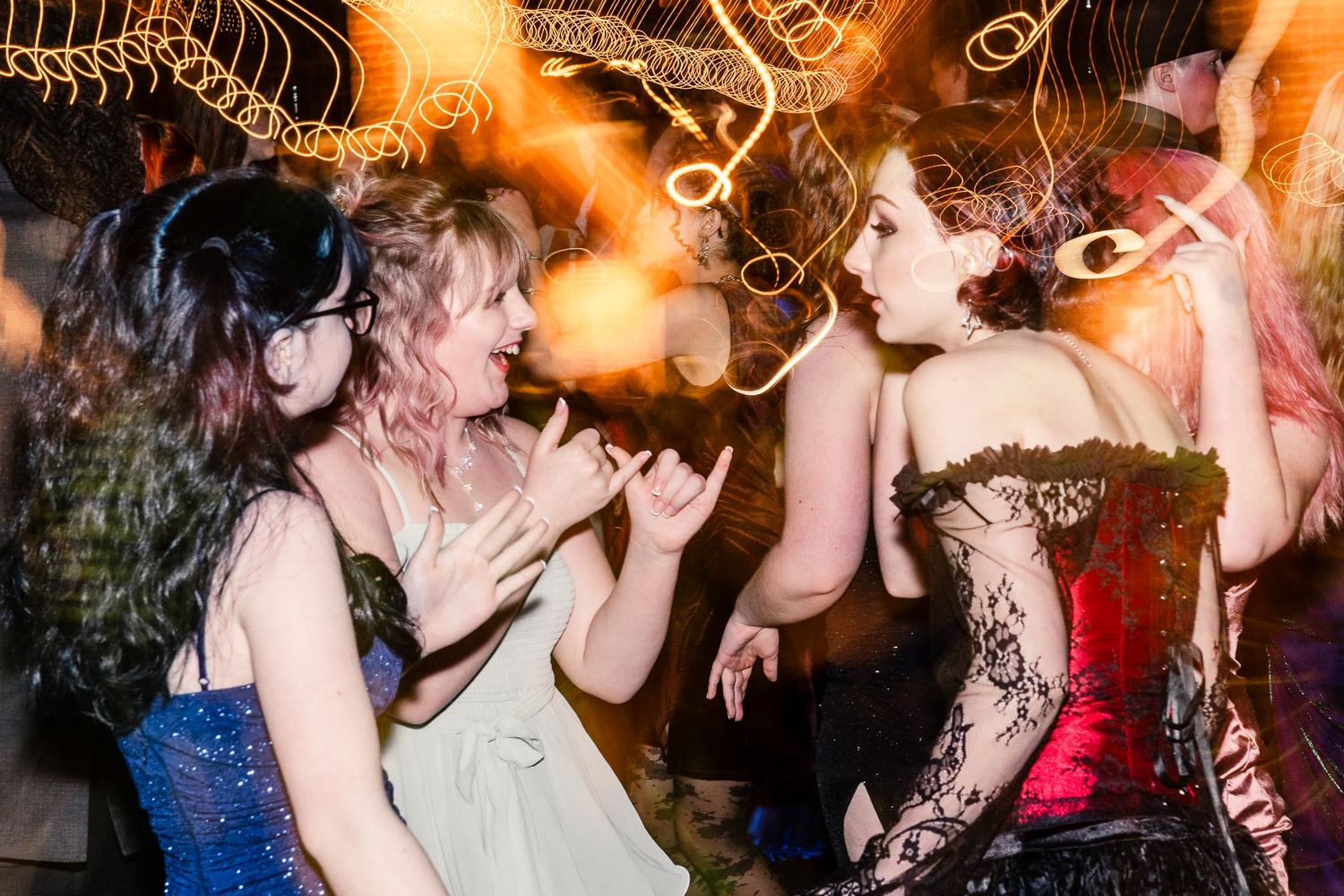 People dancing and celebrating at a lively nightclub party with orange lighting and festive atmosphere.