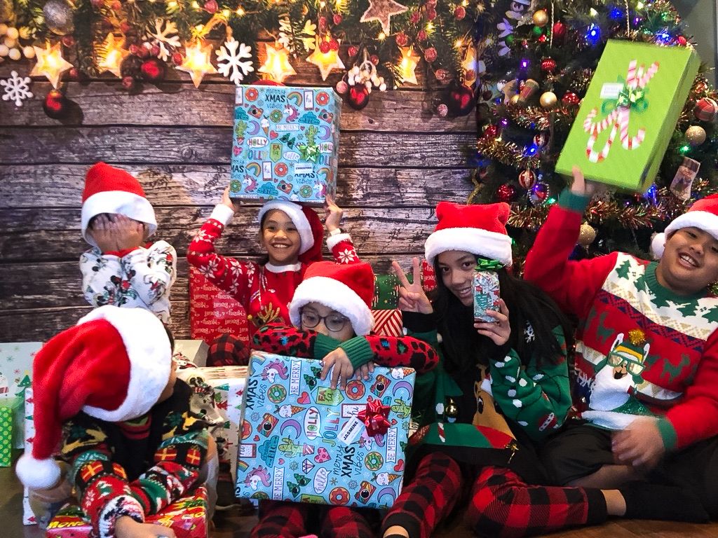 A festive collage of holiday scenes showing wrapped Christmas presents, decorations, and people in Santa hats celebrating.