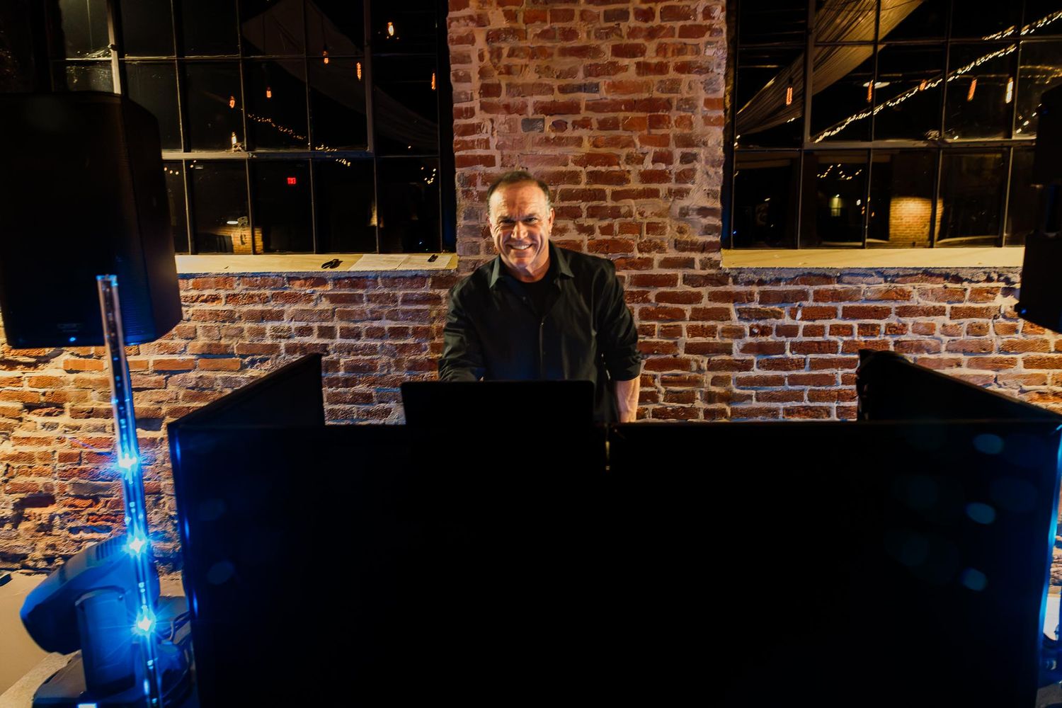 A dimly lit bar with exposed brick walls and glowing blue lights creating a moody atmosphere.