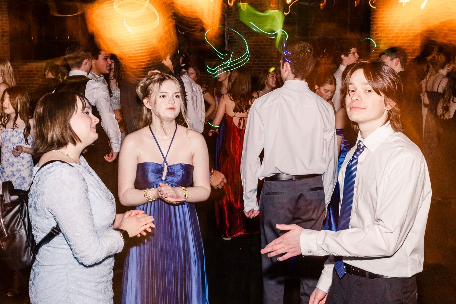 People dancing and socializing at a formal event with warm lighting and festive atmosphere.