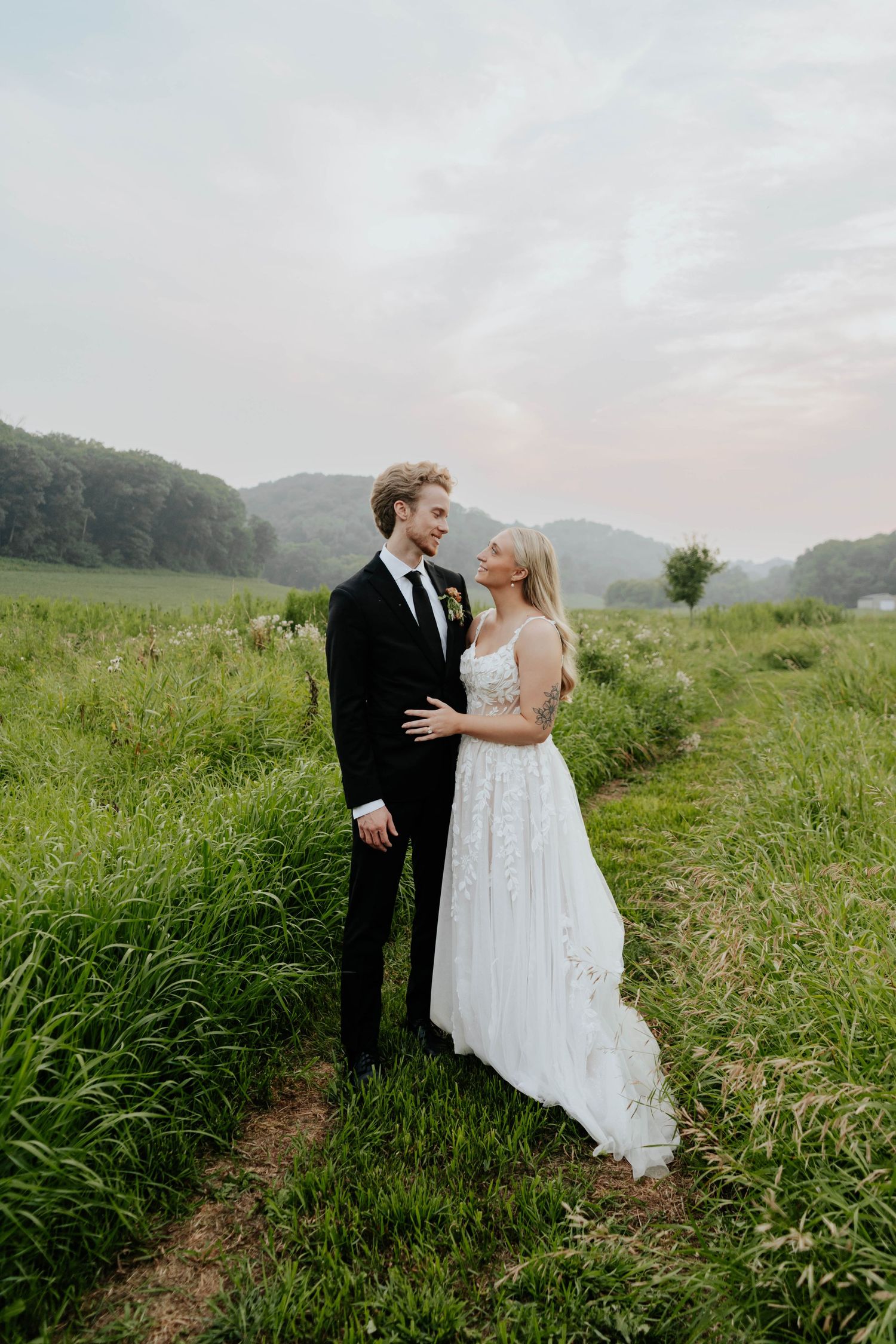 Couple embracing in misty field during wedding portrait session.
