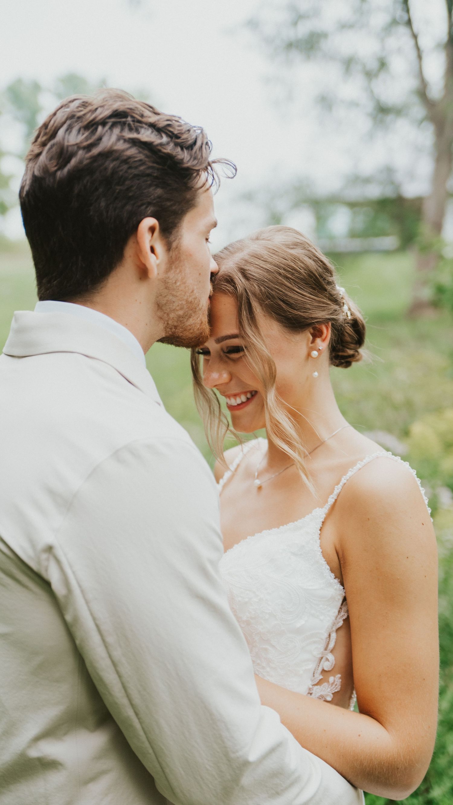 A romantic moment between newlyweds sharing intimate glances and laughter during their outdoor wedding photoshoot.