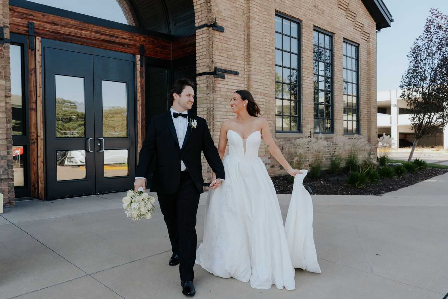 Wedding portraits captured outside historic brick building with large windows.