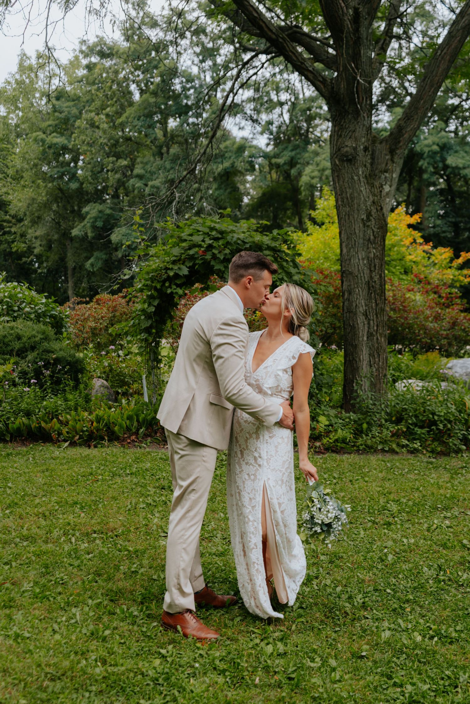 Couple sharing romantic moment in garden setting during wedding photoshoot.