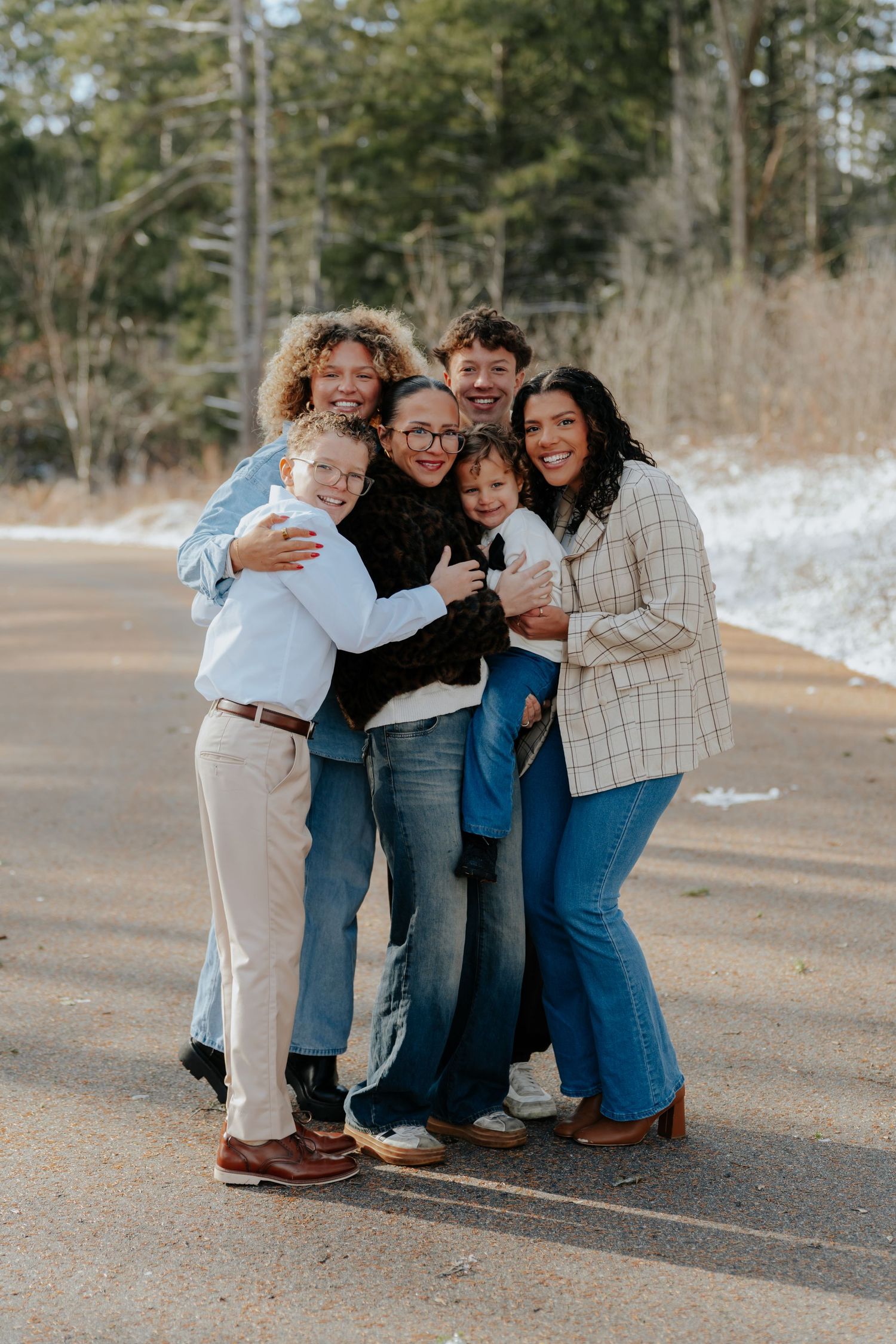 A group of friends share a joyful embrace while crouching together outdoors on a winter day.