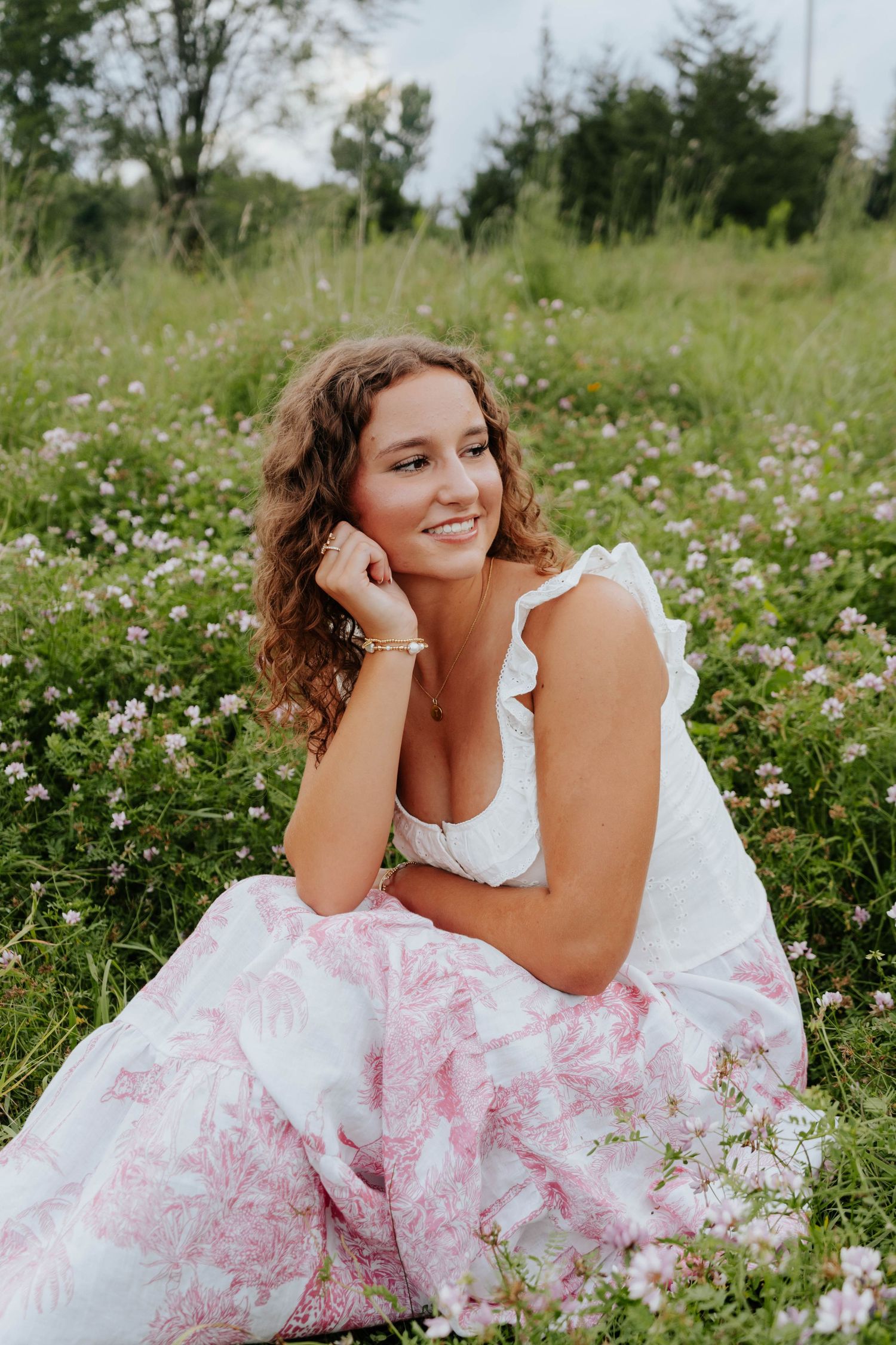 Woman in white dress lying gracefully among pink wildflowers in a summer meadow.