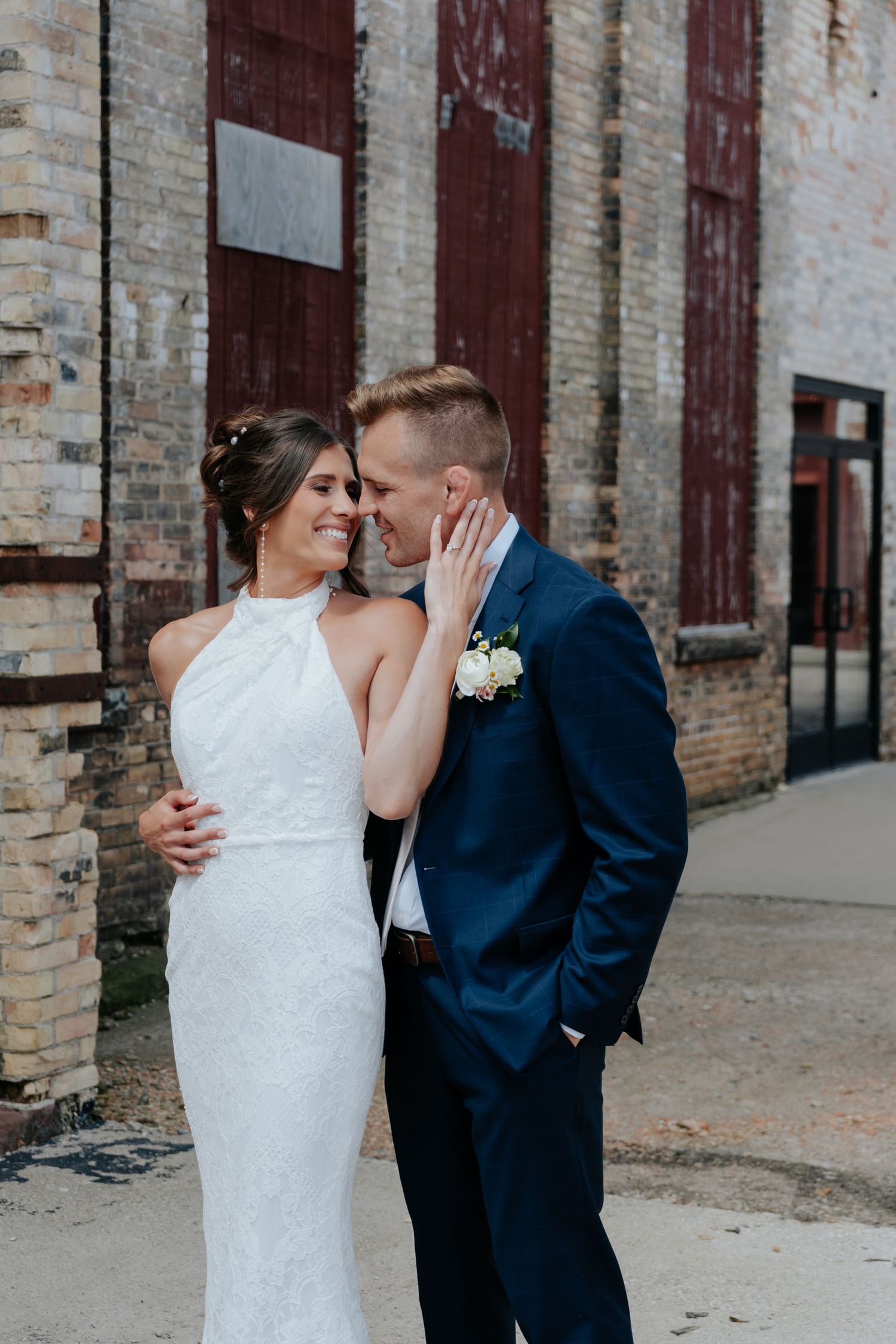 Couple sharing intimate moment against industrial brick wall backdrop.