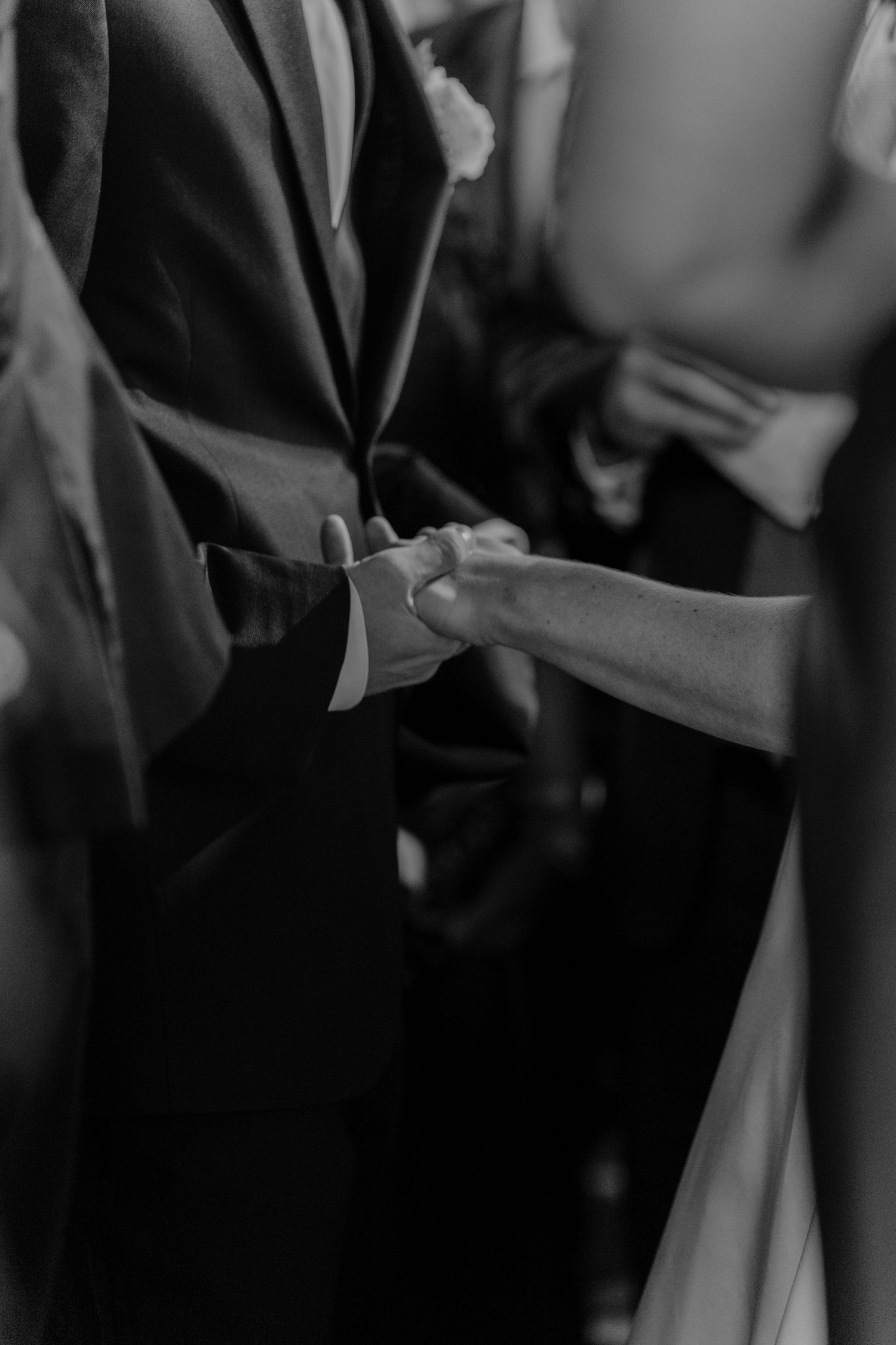 Black and white photo of a bride and groom holding hands during their wedding ceremony.