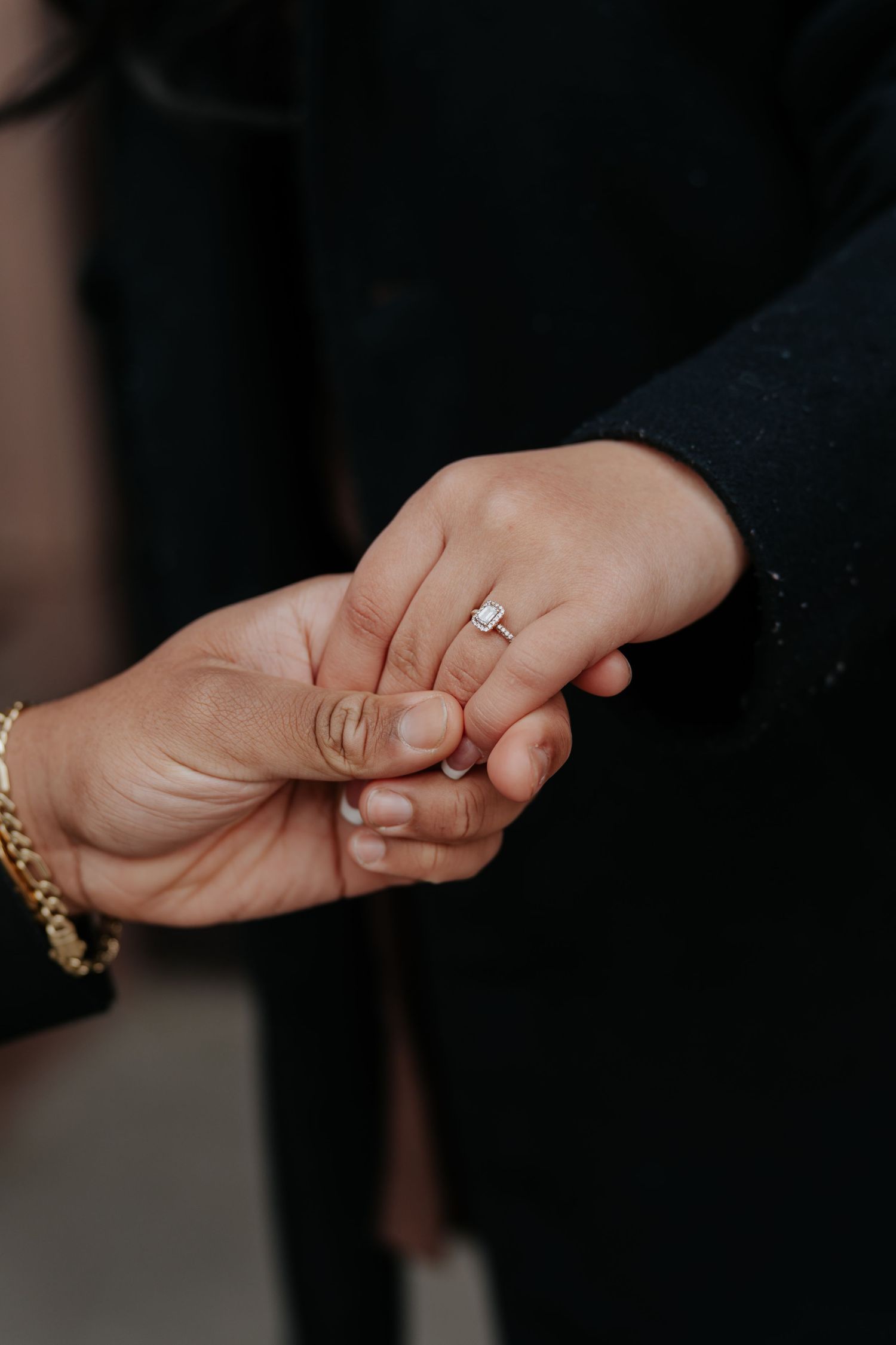 Close-up of hands holding showing a diamond solitaire engagement ring on woman's finger.