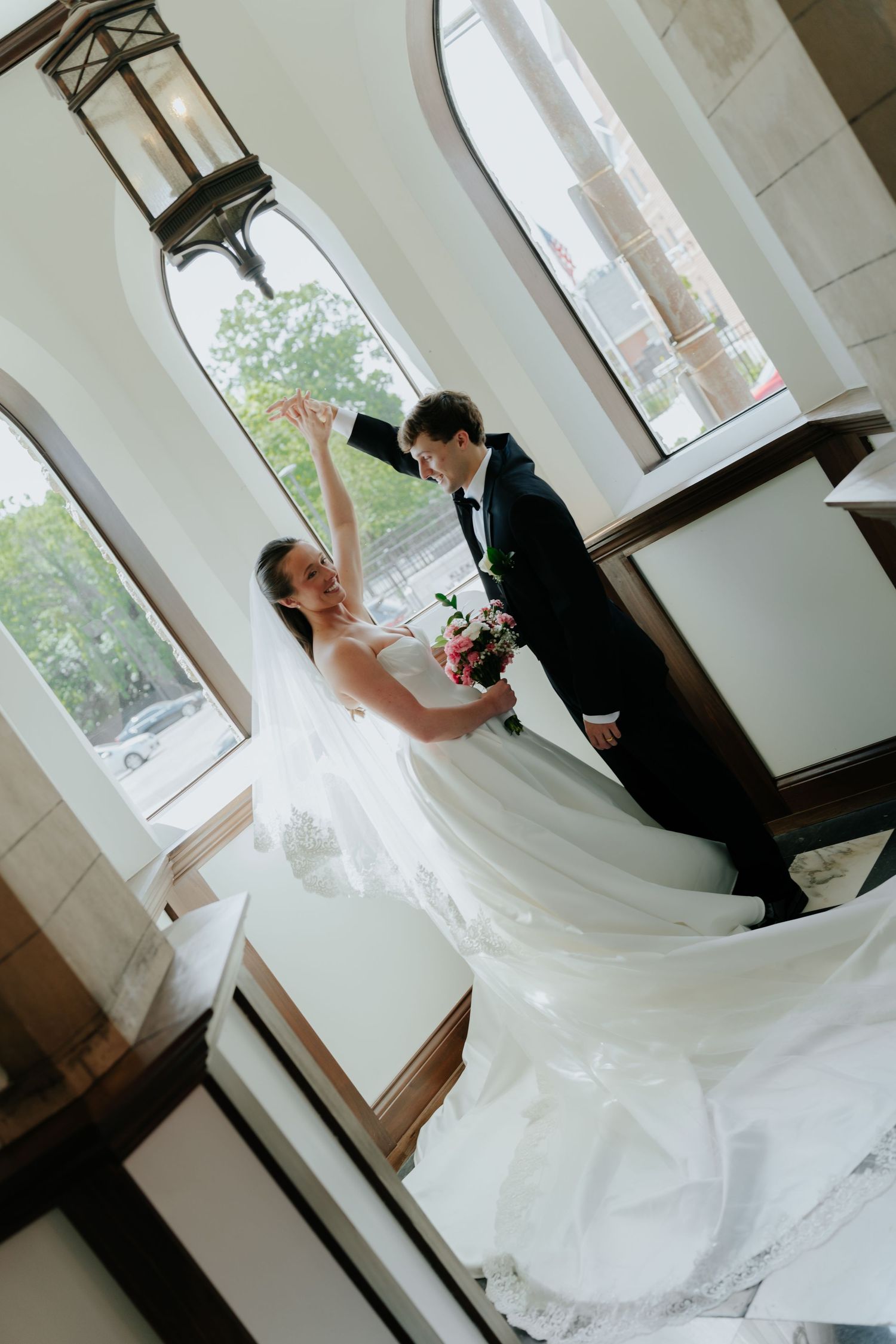 Bride and groom share a romantic dance inside an elegant chapel with arched windows and warm lighting.