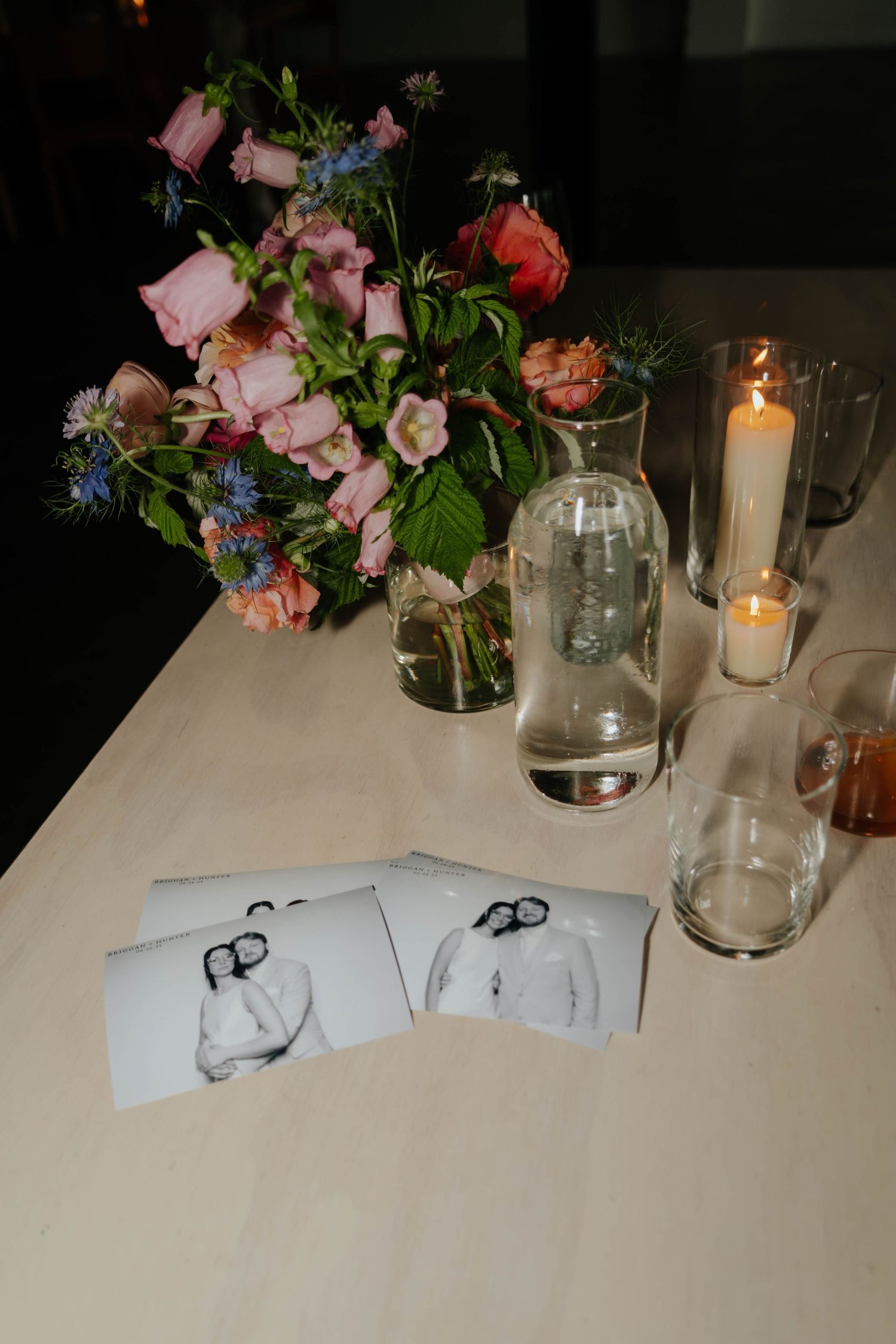 Wedding reception table setting with pink floral arrangements and glowing candles.