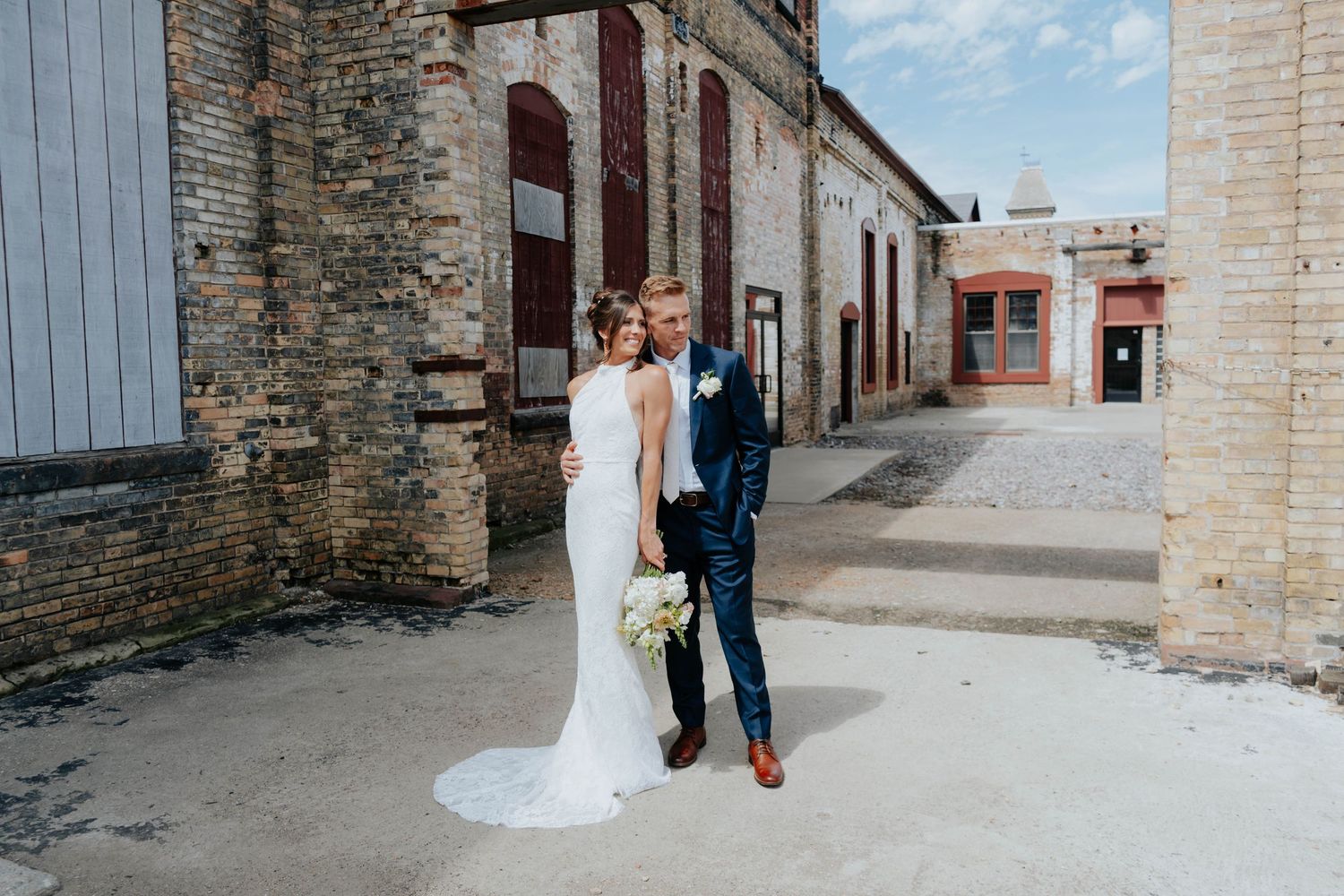 A couple walks through historic stone buildings during their wedding photoshoot.